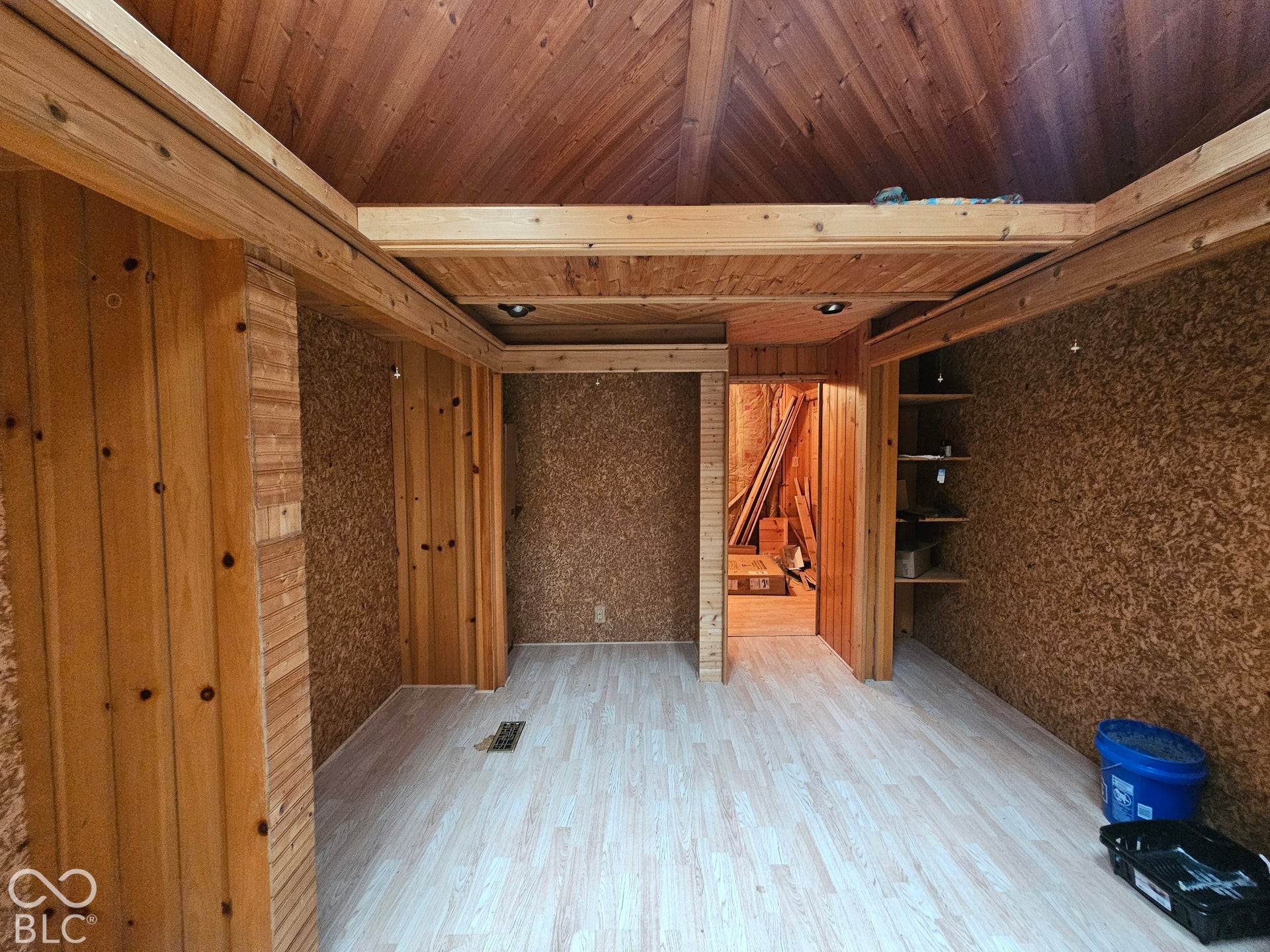Interior space featuring wood-plank paneled ceiling and walls, textured wall treatments, wood-finish flooring, and built-in wooden shelving