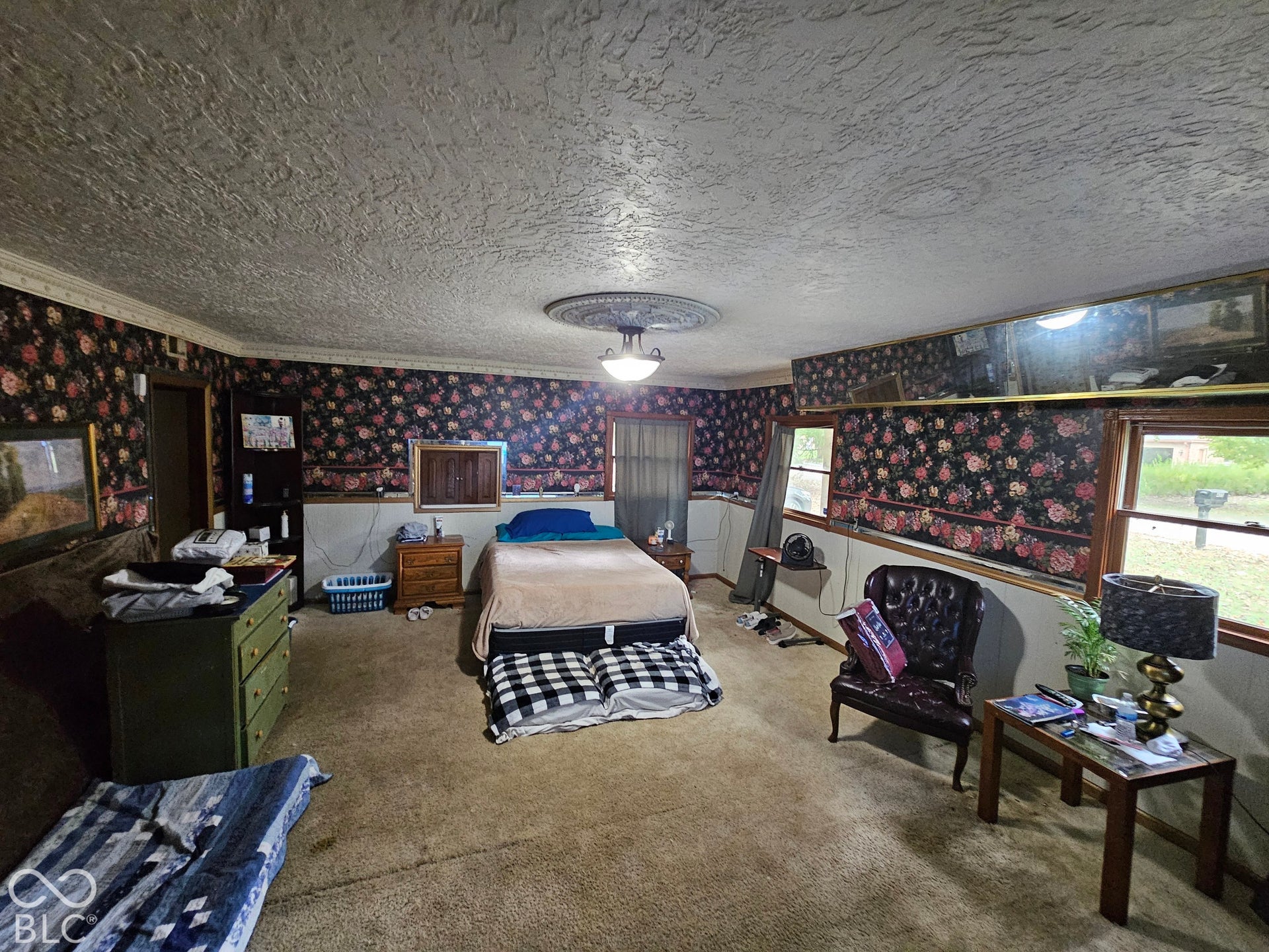 Spacious interior featuring patterned wallpaper, textured ceiling, ceiling medallion, and crown molding