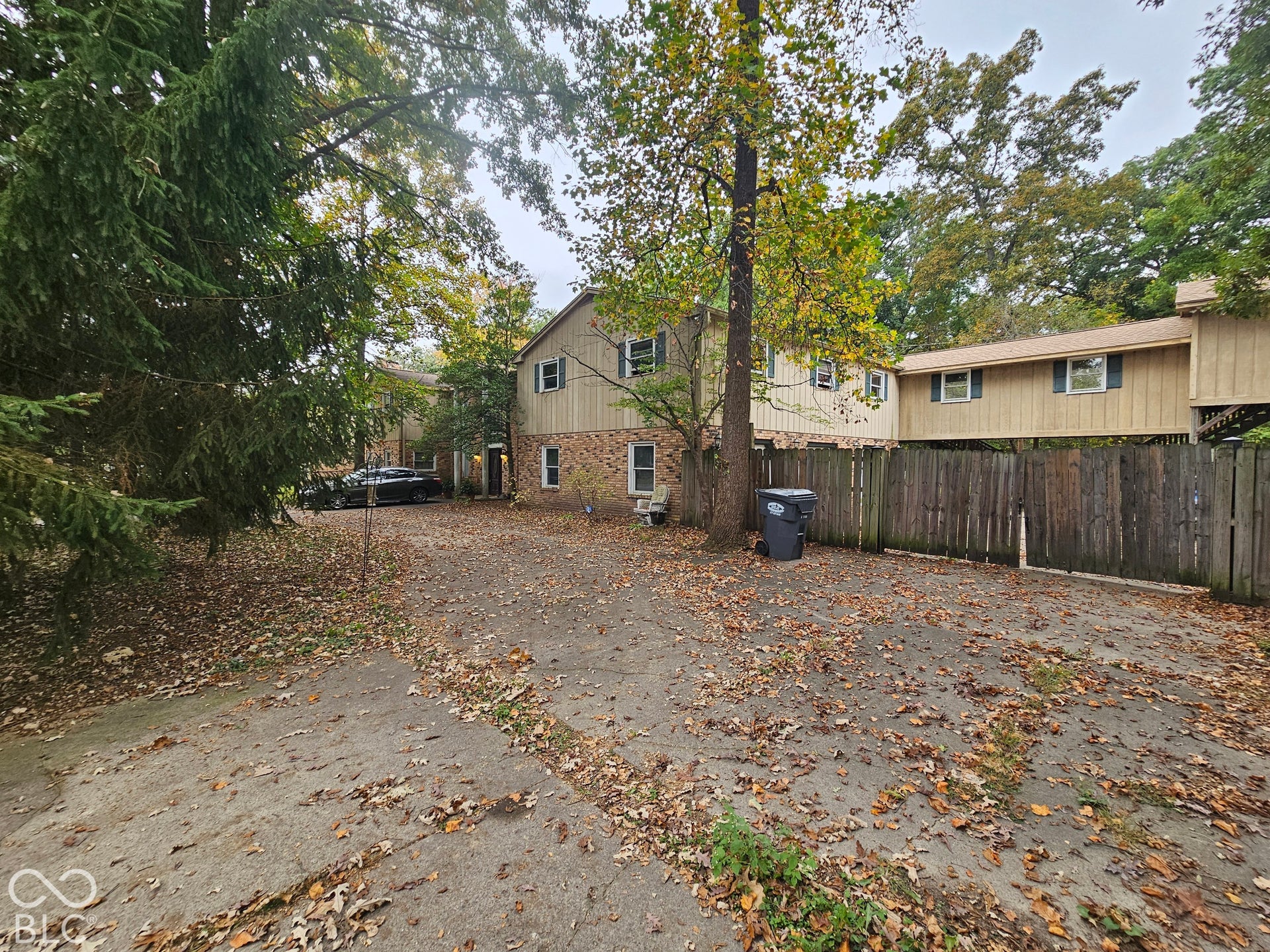 Two-story exterior featuring brick and siding facade, concrete driveway, and wooden privacy fencing