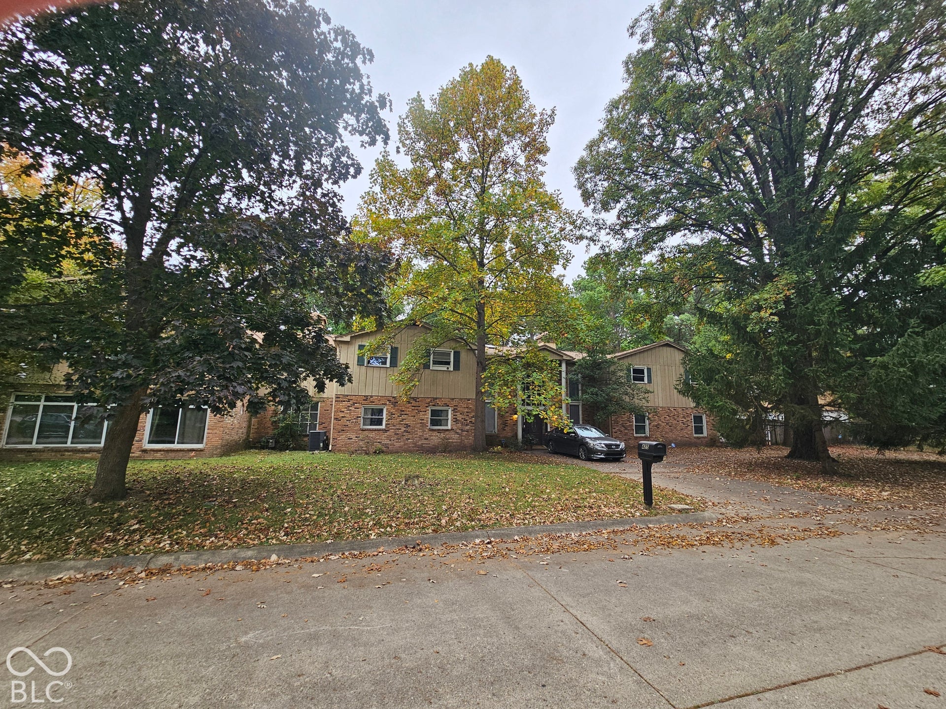 Two-story residence featuring a brick and siding exterior, large windows, and mature trees on a landscaped lot