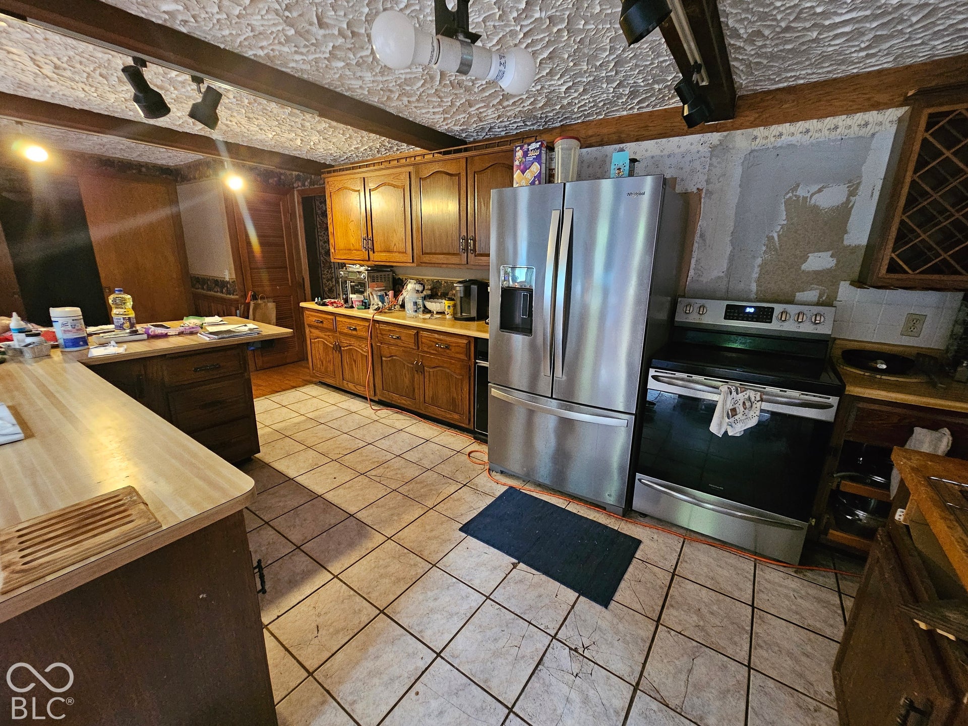Kitchen featuring stained wood cabinetry, ceramic tile flooring, built-in wine rack, and stainless steel appliances