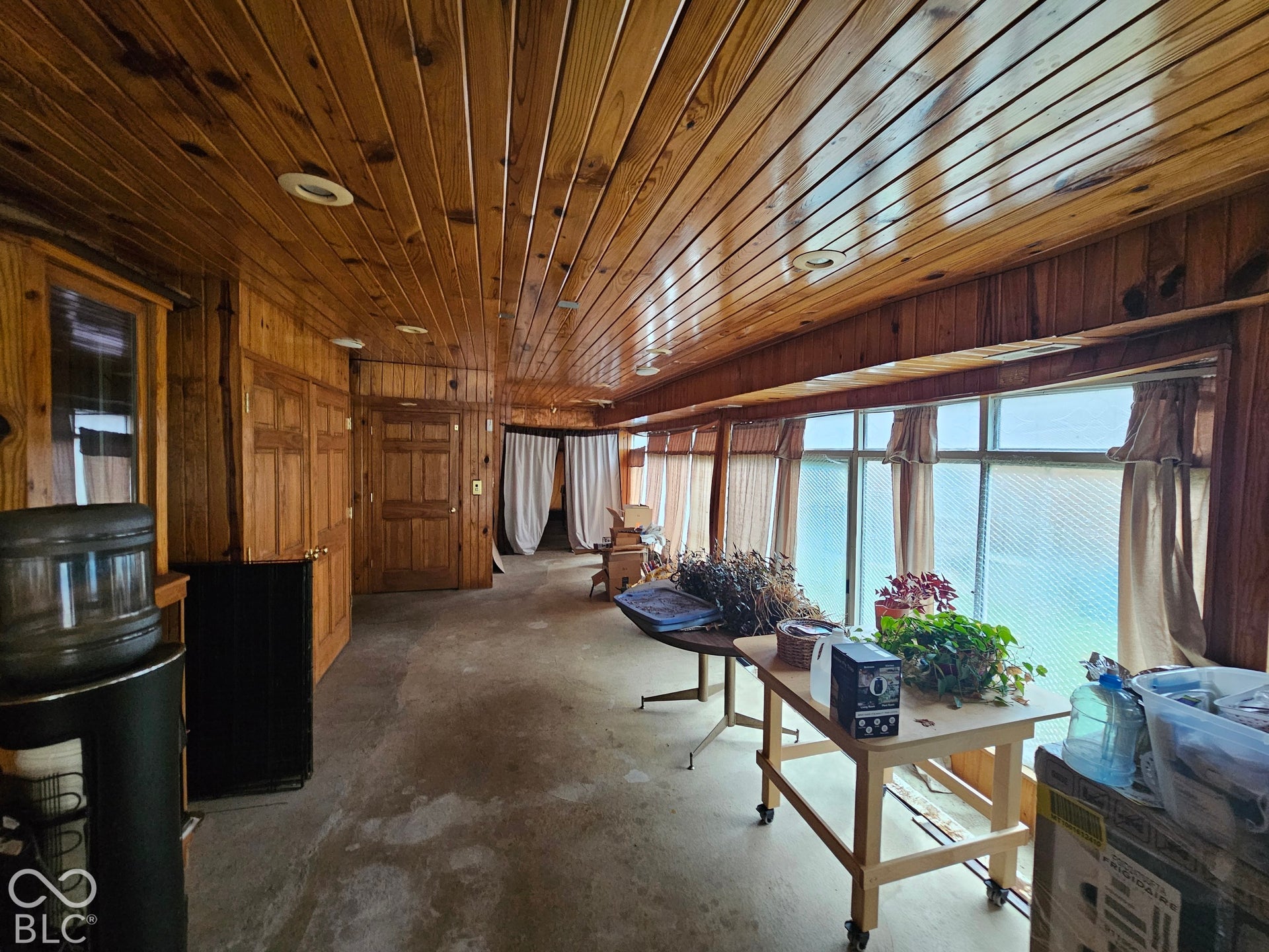 Interior space featuring extensive wood-paneled walls and ceiling, recessed lighting, and a multi-panel window configuration