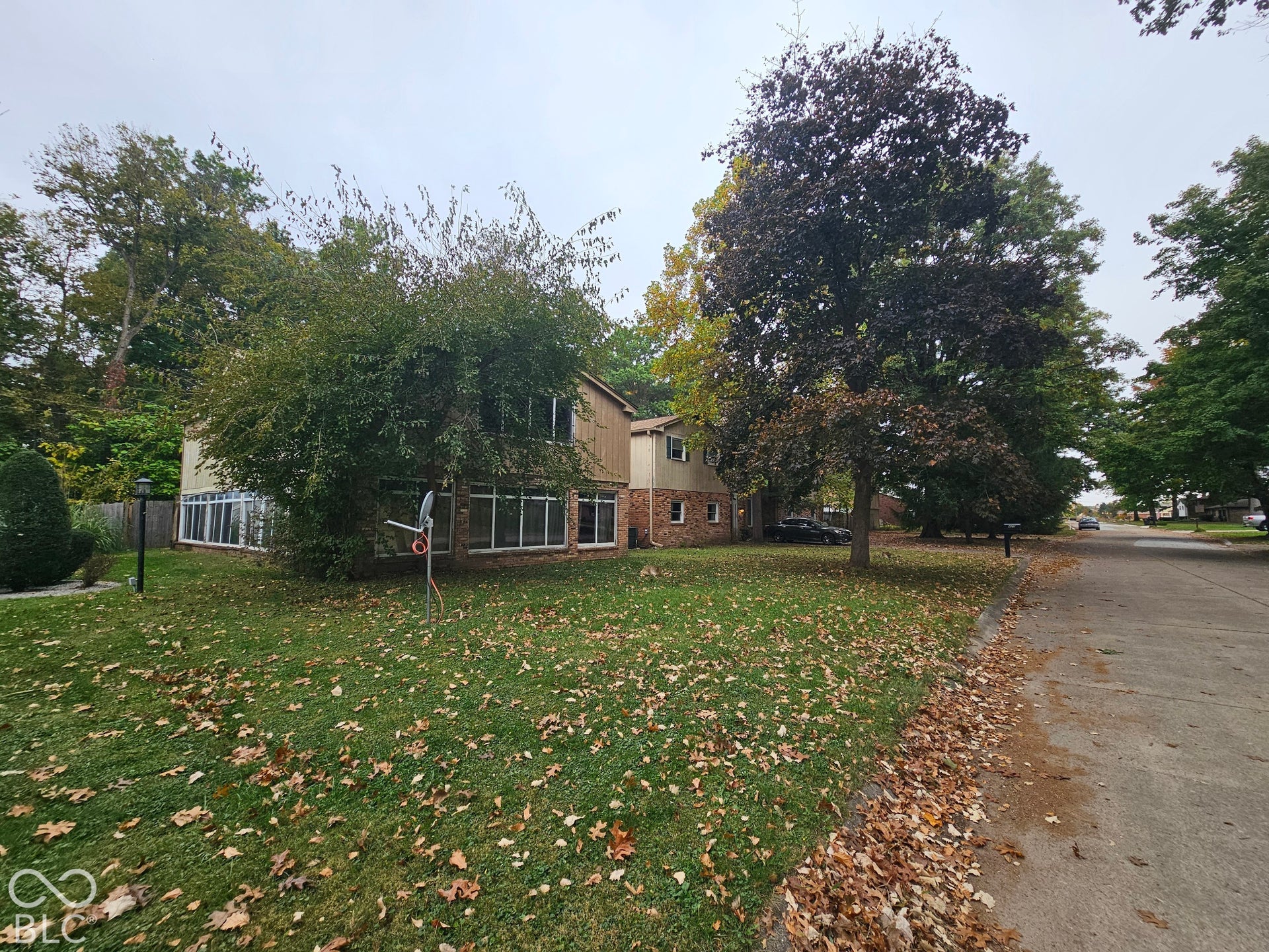 Split-level exterior featuring a brick and siding facade, extensive multi-pane window configuration, and mature trees on a corner lot