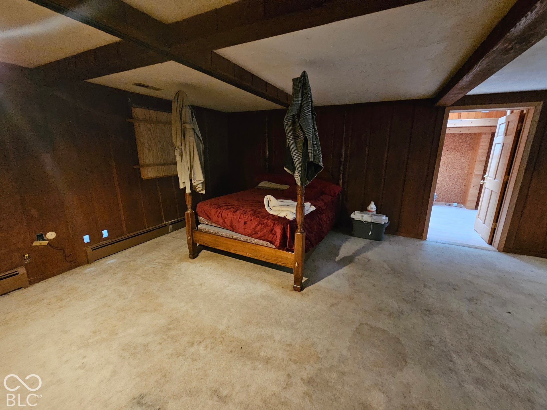 Interior space featuring wood-paneled walls, exposed ceiling beams, and a six-panel interior door