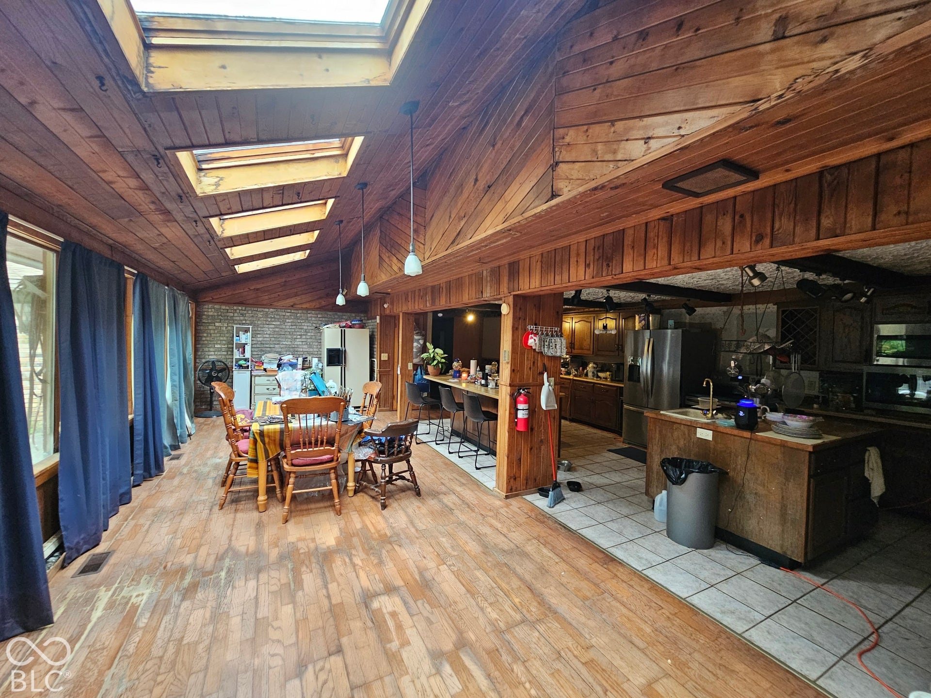 Vaulted wood-plank ceiling featuring integrated skylights, wood-panel wall accents, and pendant lighting