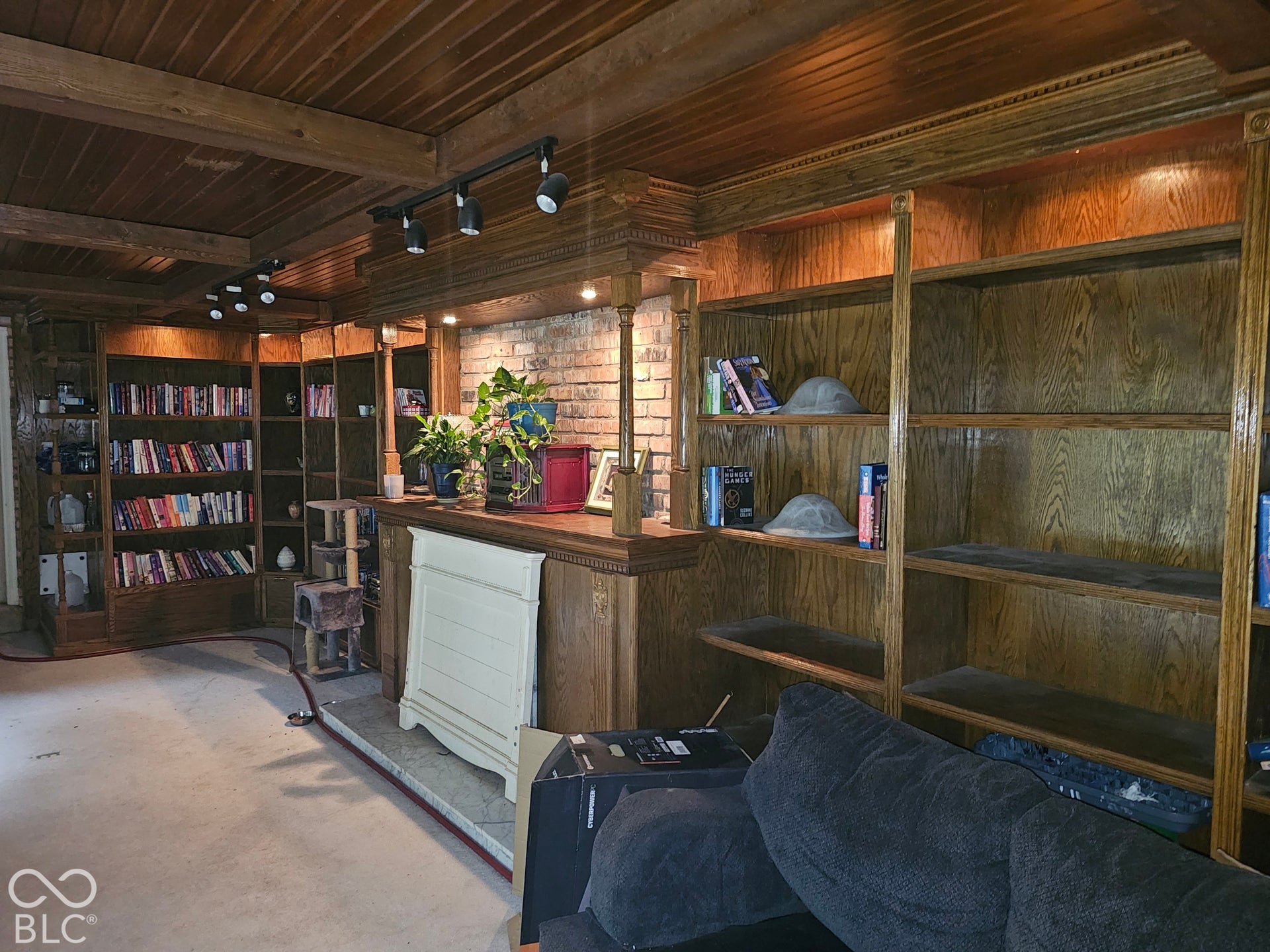Custom floor-to-ceiling wood cabinetry, exposed brick fireplace surround, decorative wood-paneled ceiling, and adjustable track lighting