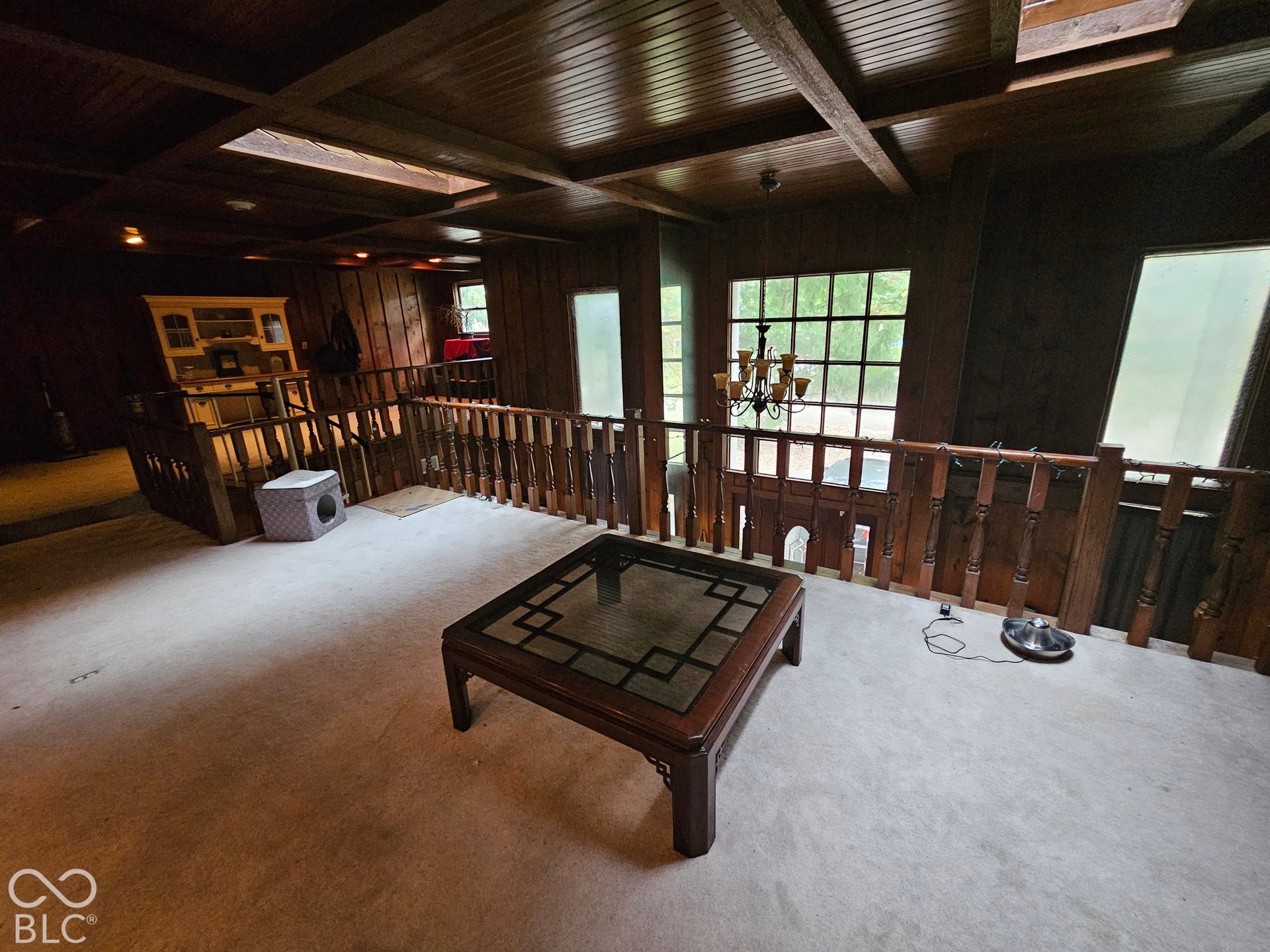 Exposed beam ceiling with wood-paneled detailing, wood-plank railing, built-in cabinetry, and multi-pane windows
