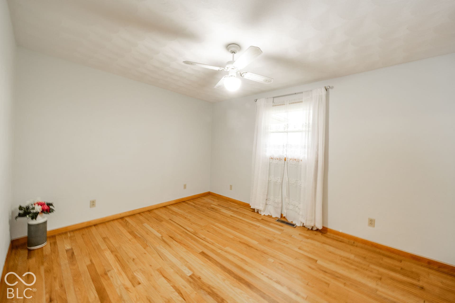 Room featuring wood-finish flooring, textured ceiling, and white ceiling fan with integrated lighting