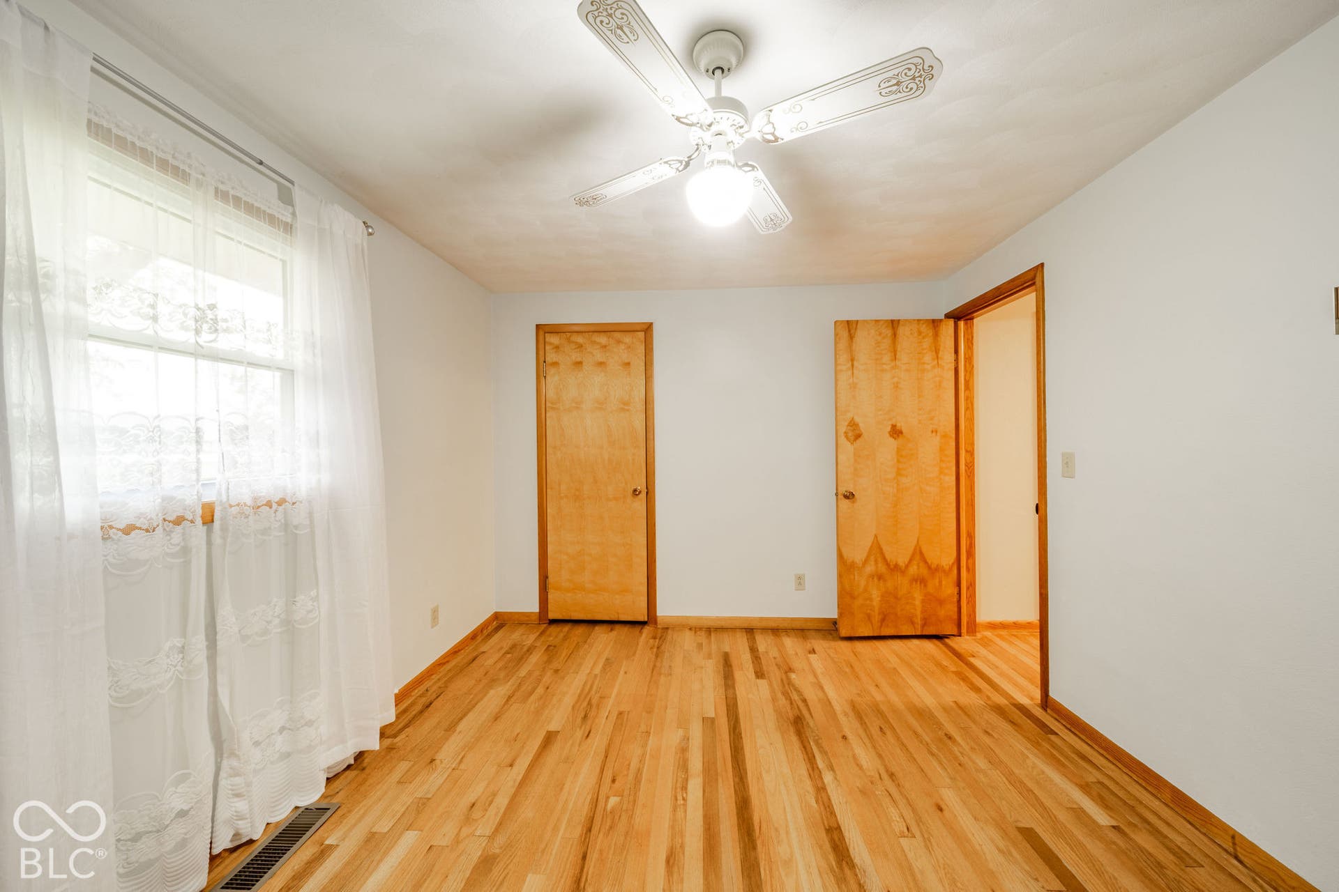 Wood-finish flooring, ceiling fan with integrated lighting, and natural wood-finish interior doors
