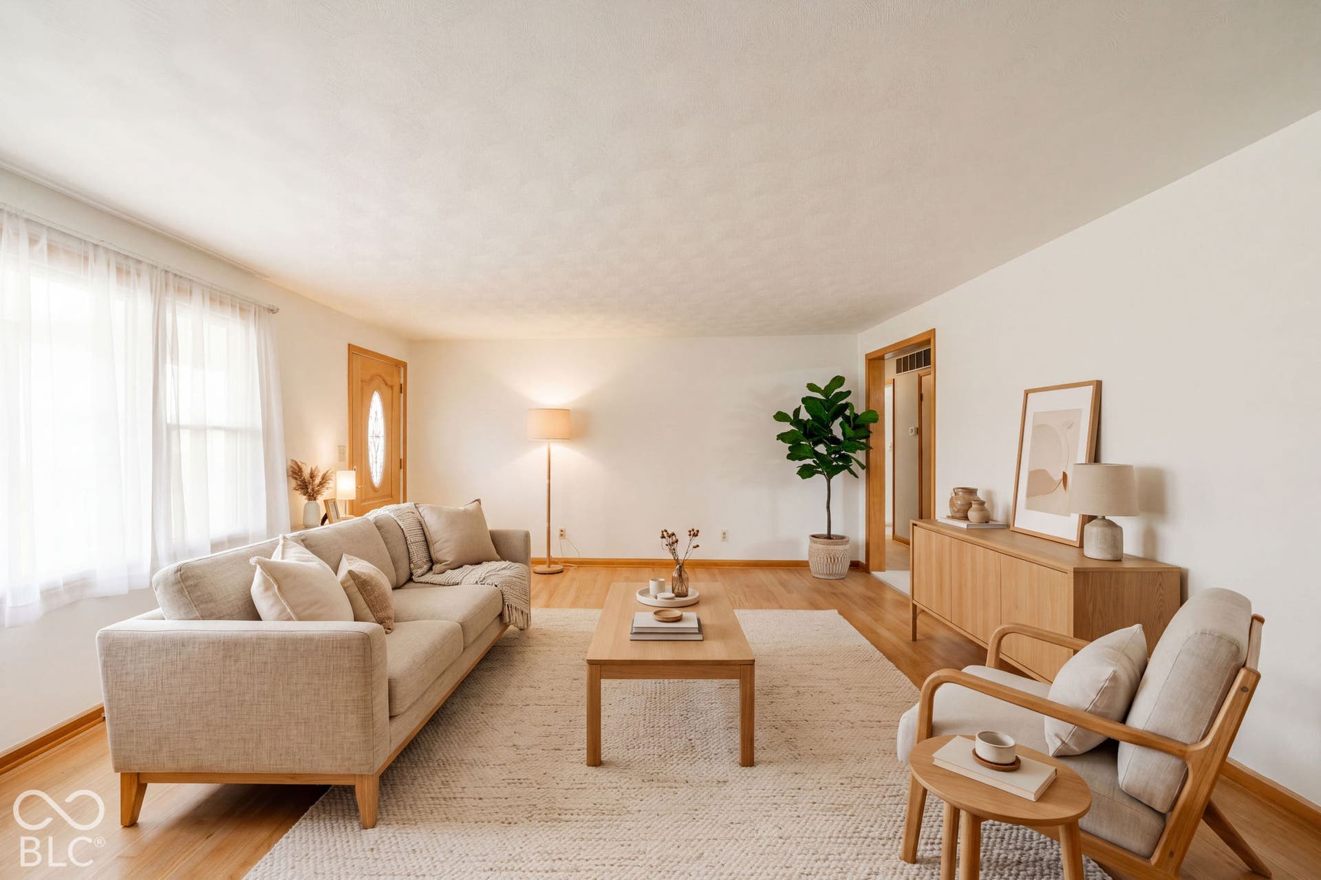 Virtually Altered - Living area featuring wood-finish flooring, a large window, and an oval-pane wood entry door. Virtually Staged