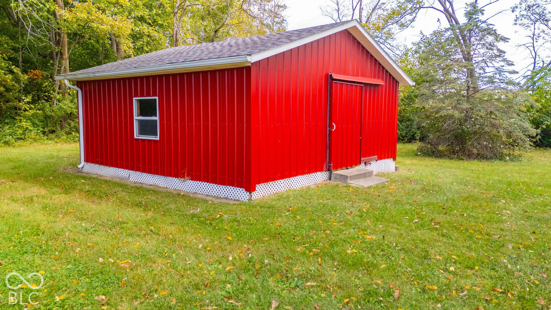 Detached storage structure with metal siding, a gable roof, concrete foundation, lattice skirting, and an entry door