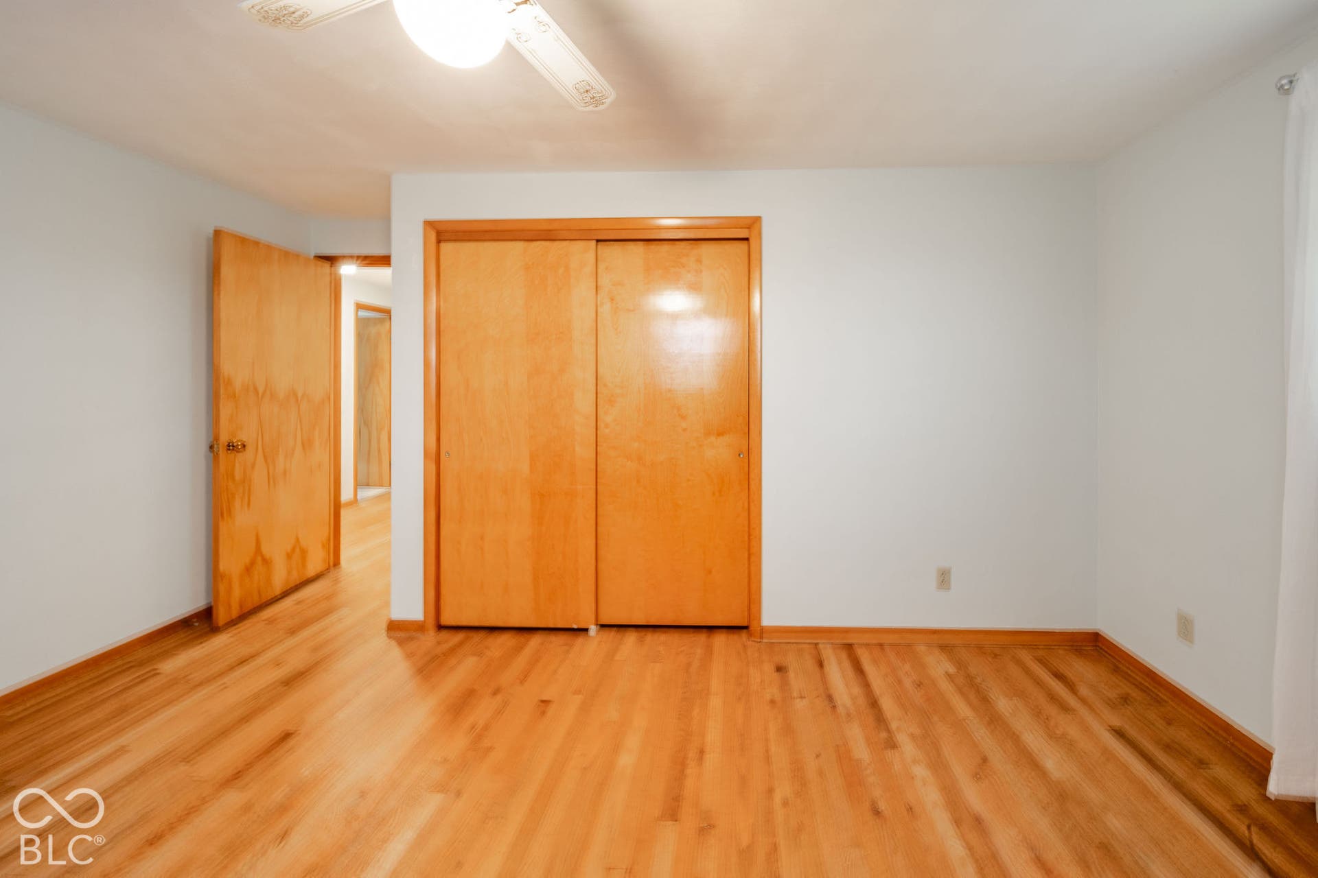 Room featuring wood-finish flooring, wood-toned interior doors, built-in sliding-door closet, and ceiling-mounted light fixture