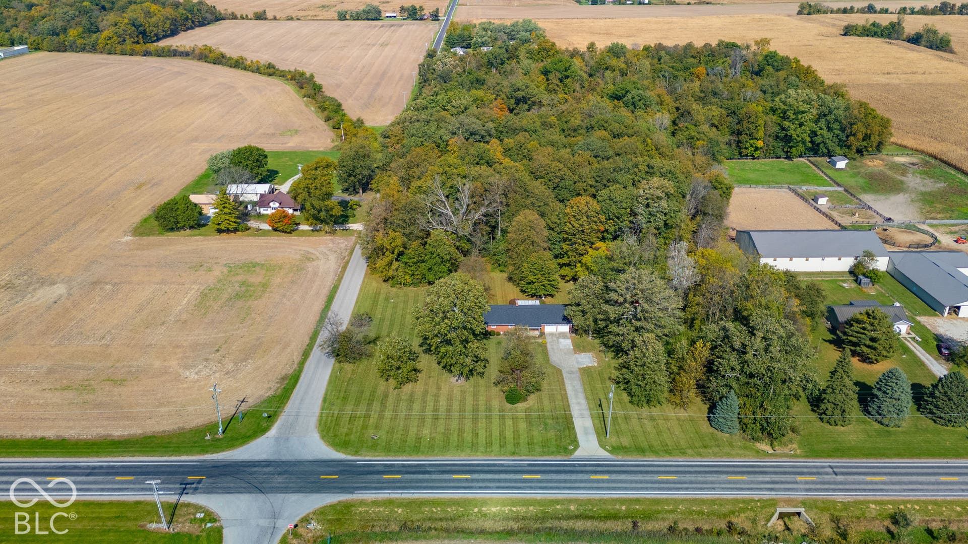 Expansive acreage featuring a private wooded area, a concrete driveway, a structured lawn, and a multi-building configuration