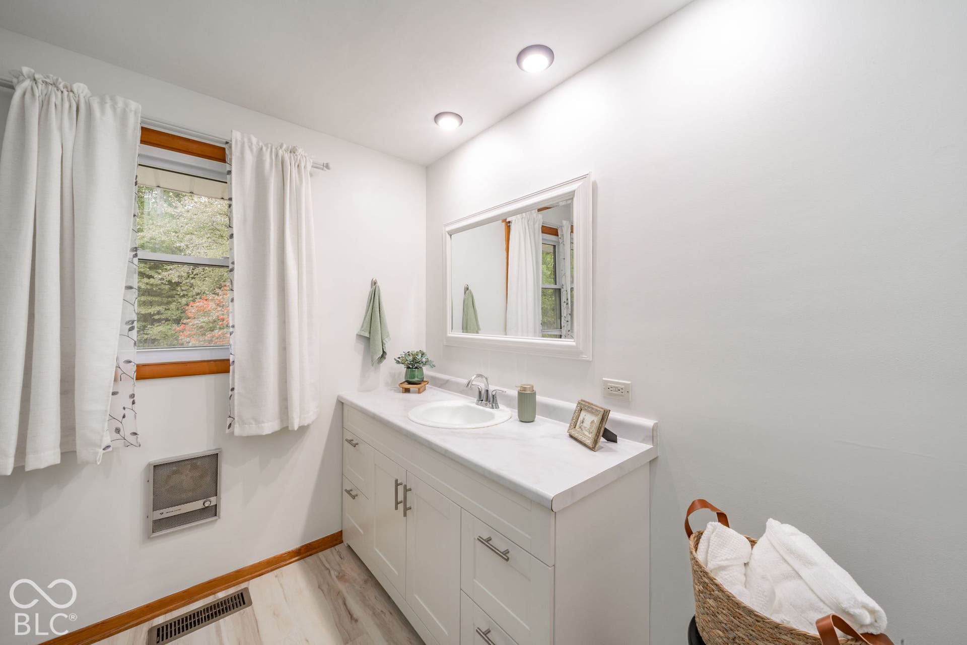 White vanity cabinet with integrated countertop, inset sink, recessed lighting, and framed mirror