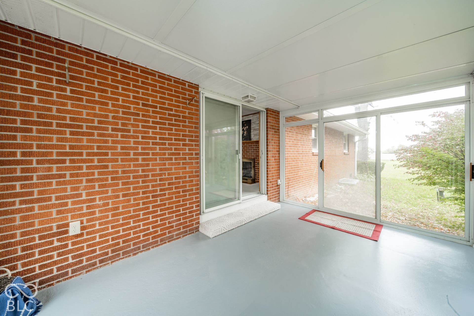 Enclosed sunroom featuring exposed brick walls, expansive sliding glass doors, and solid surface flooring