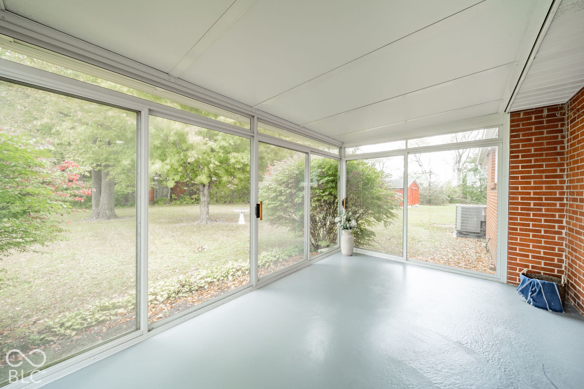 Enclosed porch featuring an expansive glass-paneled wall, solid surface flooring, and exposed brick masonry
