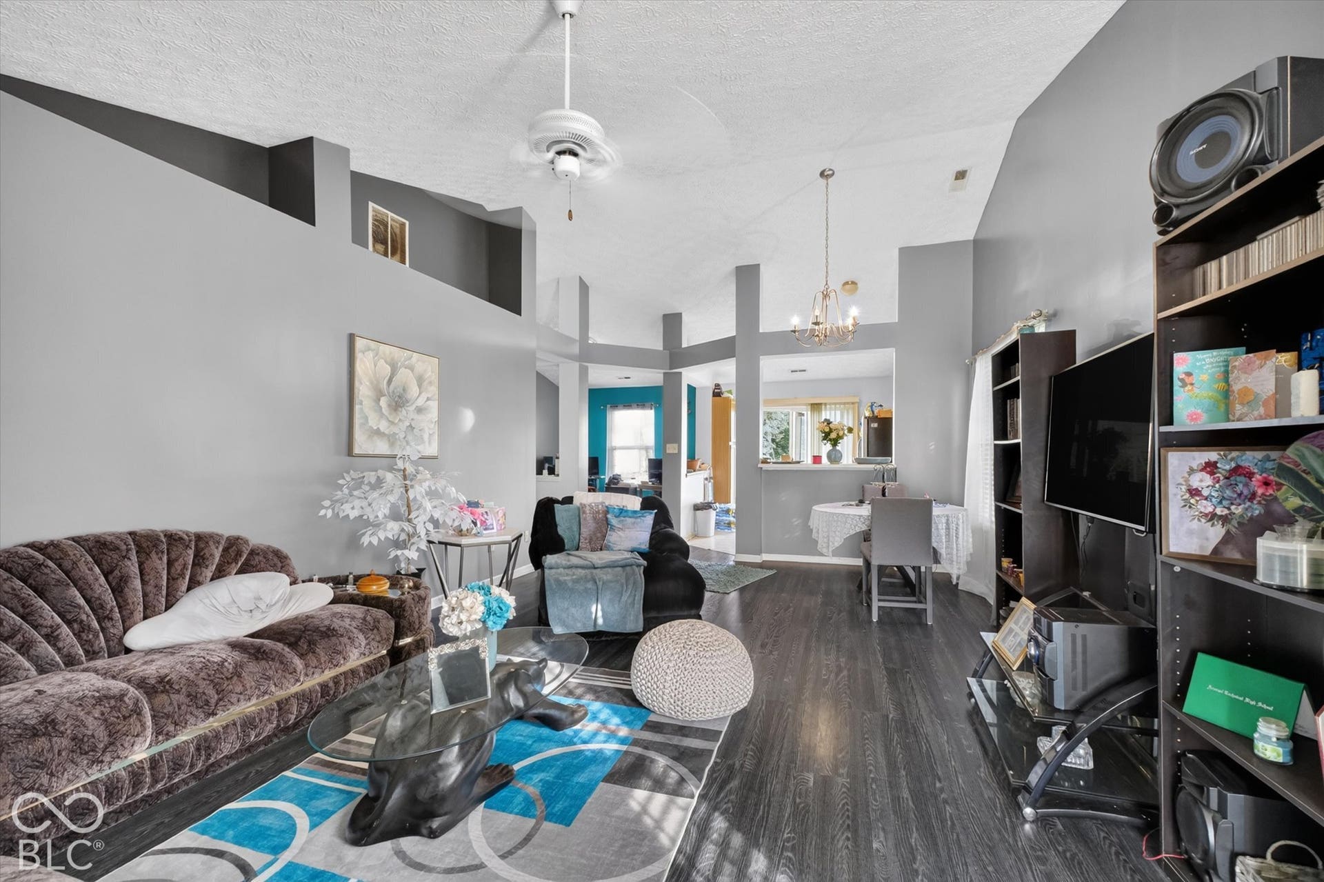 Vaulted ceilings, wood-finish flooring, ceiling fan, and multi-level architectural wall cutouts