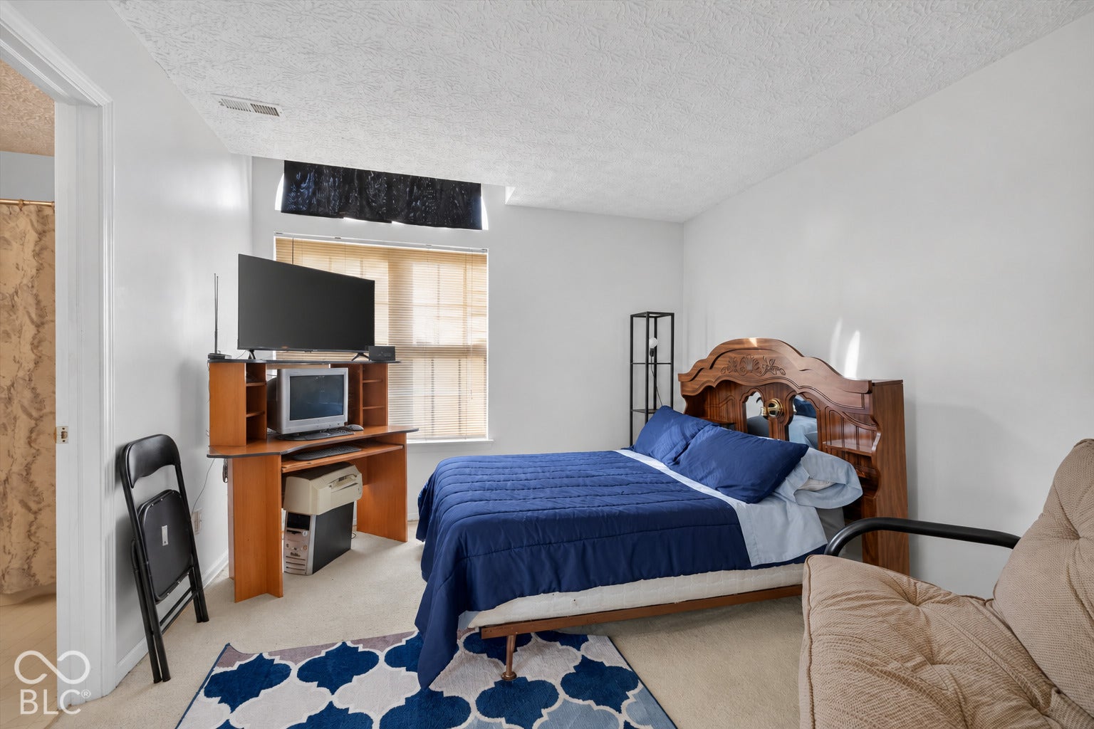 Neutral-toned carpet flooring and a single-pane window with a light-filtering shade