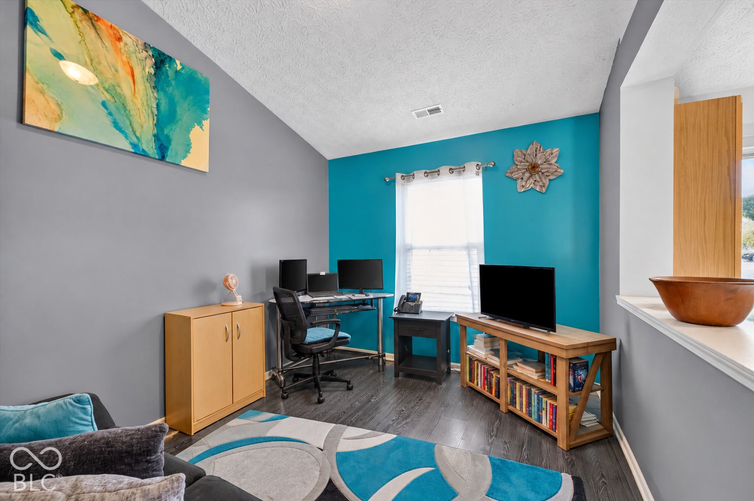 Vaulted ceiling, wood-finish flooring, and natural lighting provided by a central window