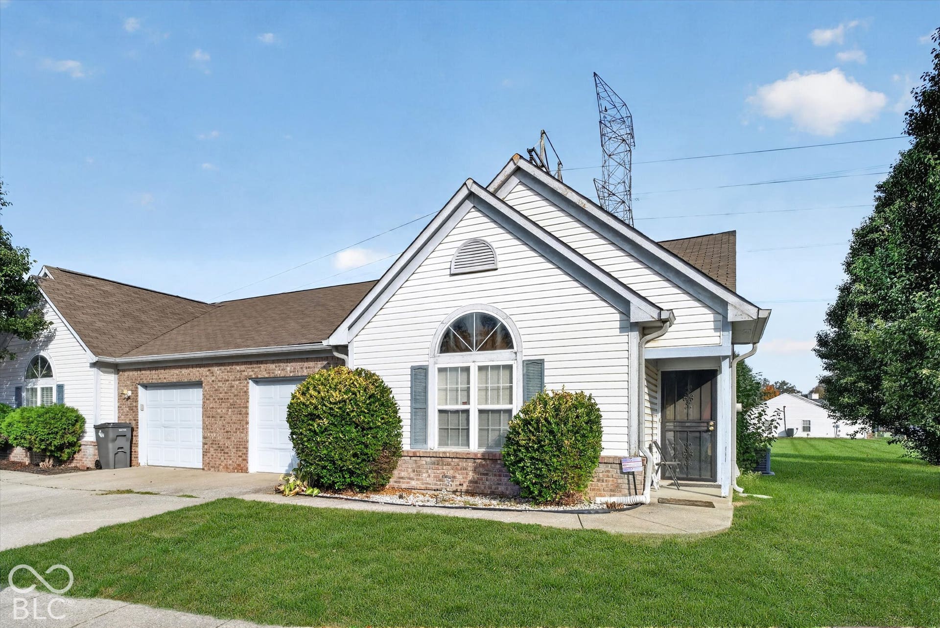 Exterior featuring horizontal siding, a brick facade accent, an arched window, and a two-car garage