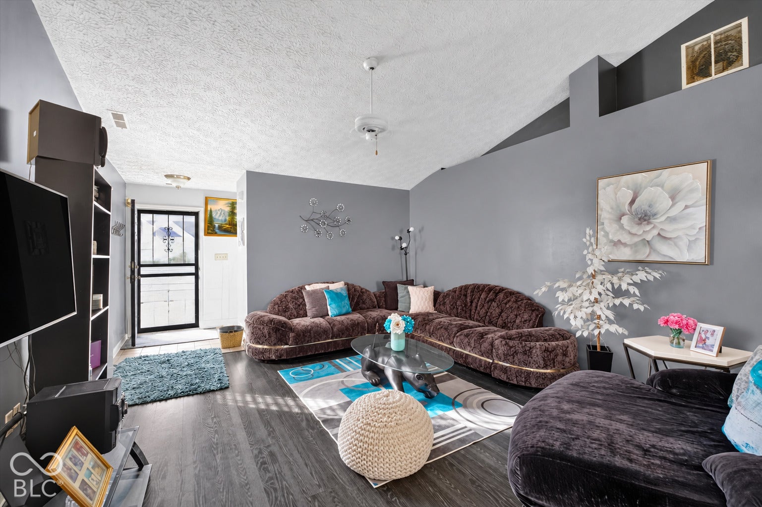 Living area featuring a vaulted ceiling, wood-finish flooring, and a ceiling fan