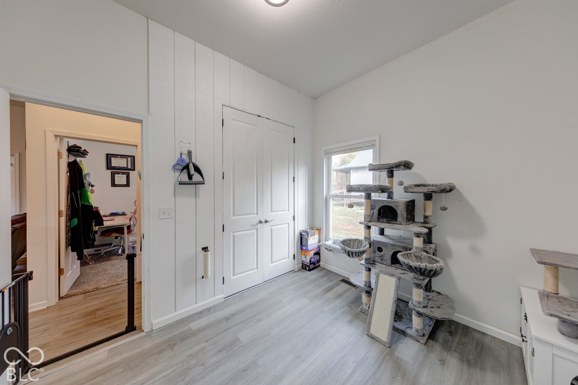 Interior room featuring wood-finish flooring, white vertical plank wall detailing, and white double doors