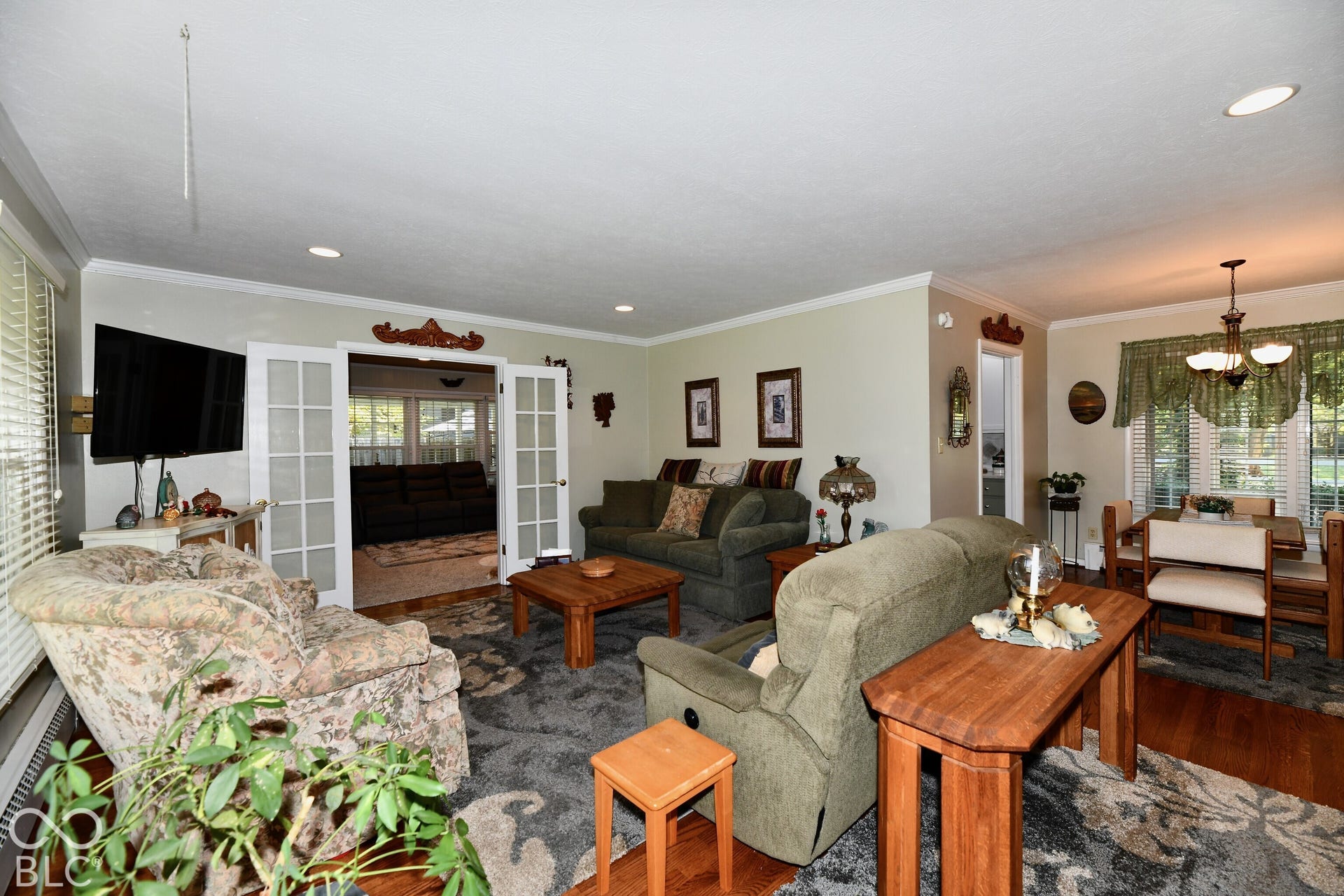Living area featuring recessed lighting, crown molding, wood-finish flooring, and white-trimmed French doors