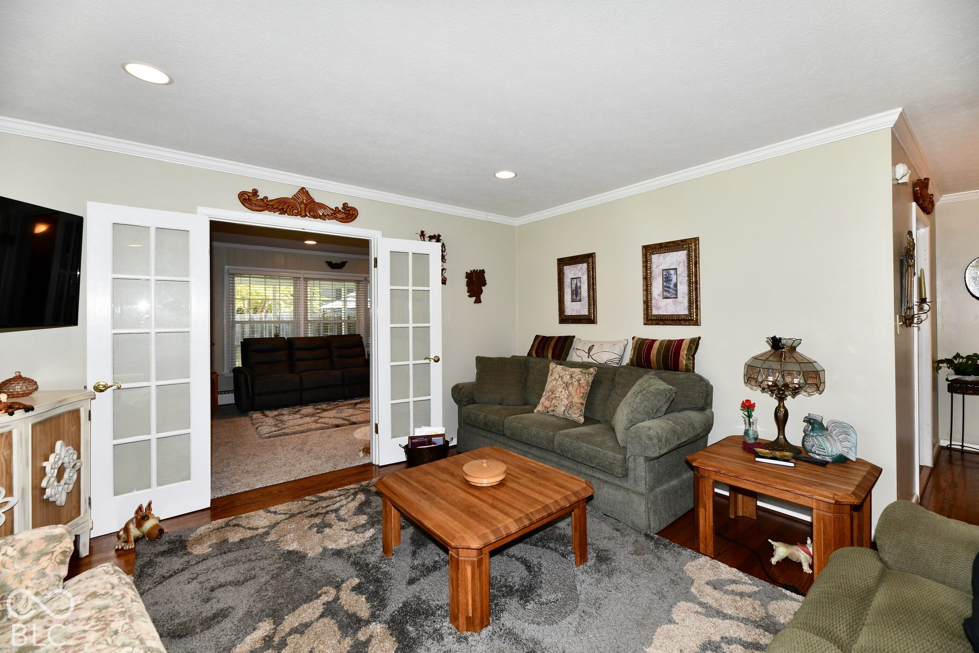 Living area featuring recessed lighting, crown molding, and glass-paned French doors with decorative pediment trim