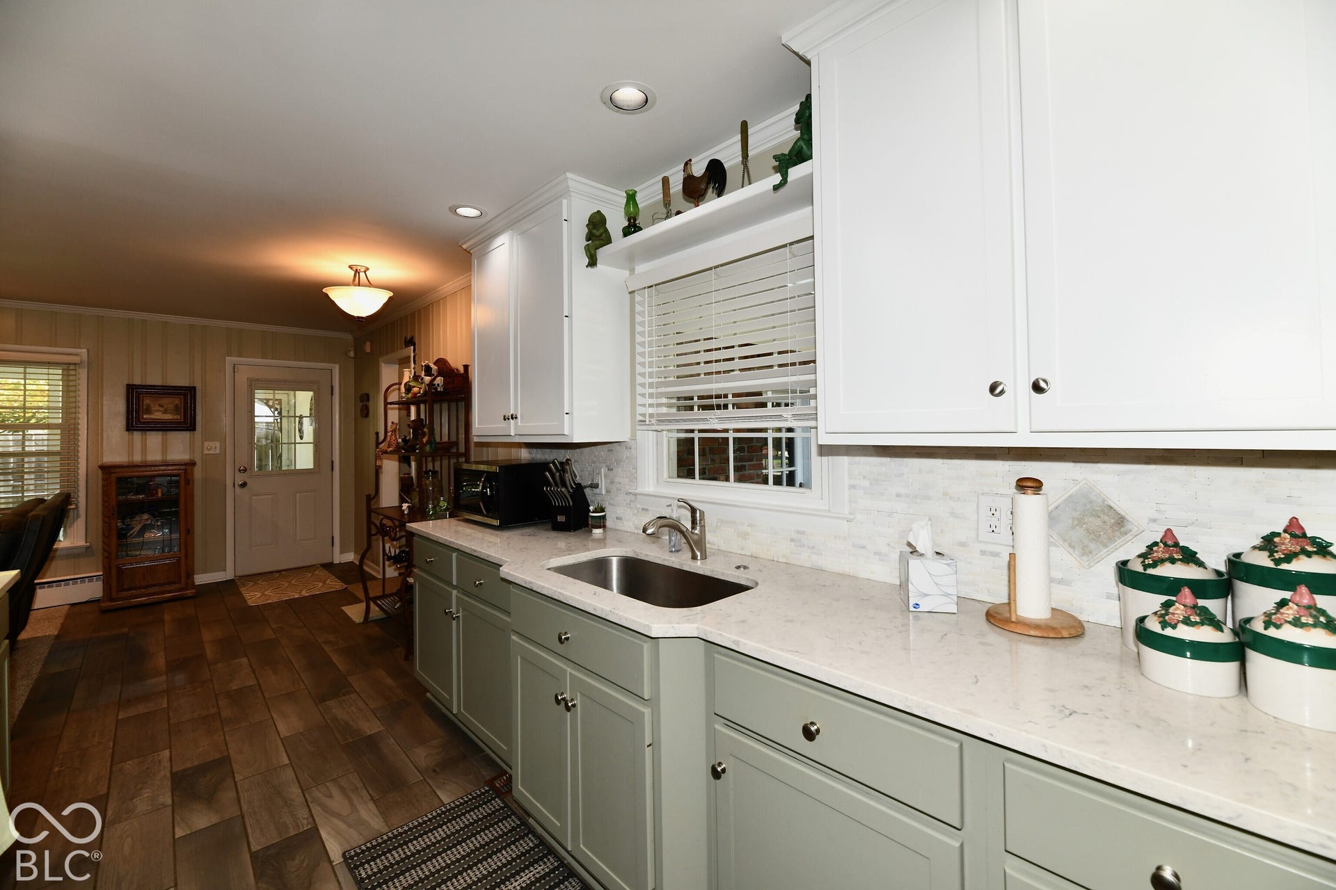Kitchen featuring white upper cabinetry, sage green lower cabinetry, stone-finish countertops, stainless steel undermount sink, and wood-finish flooring