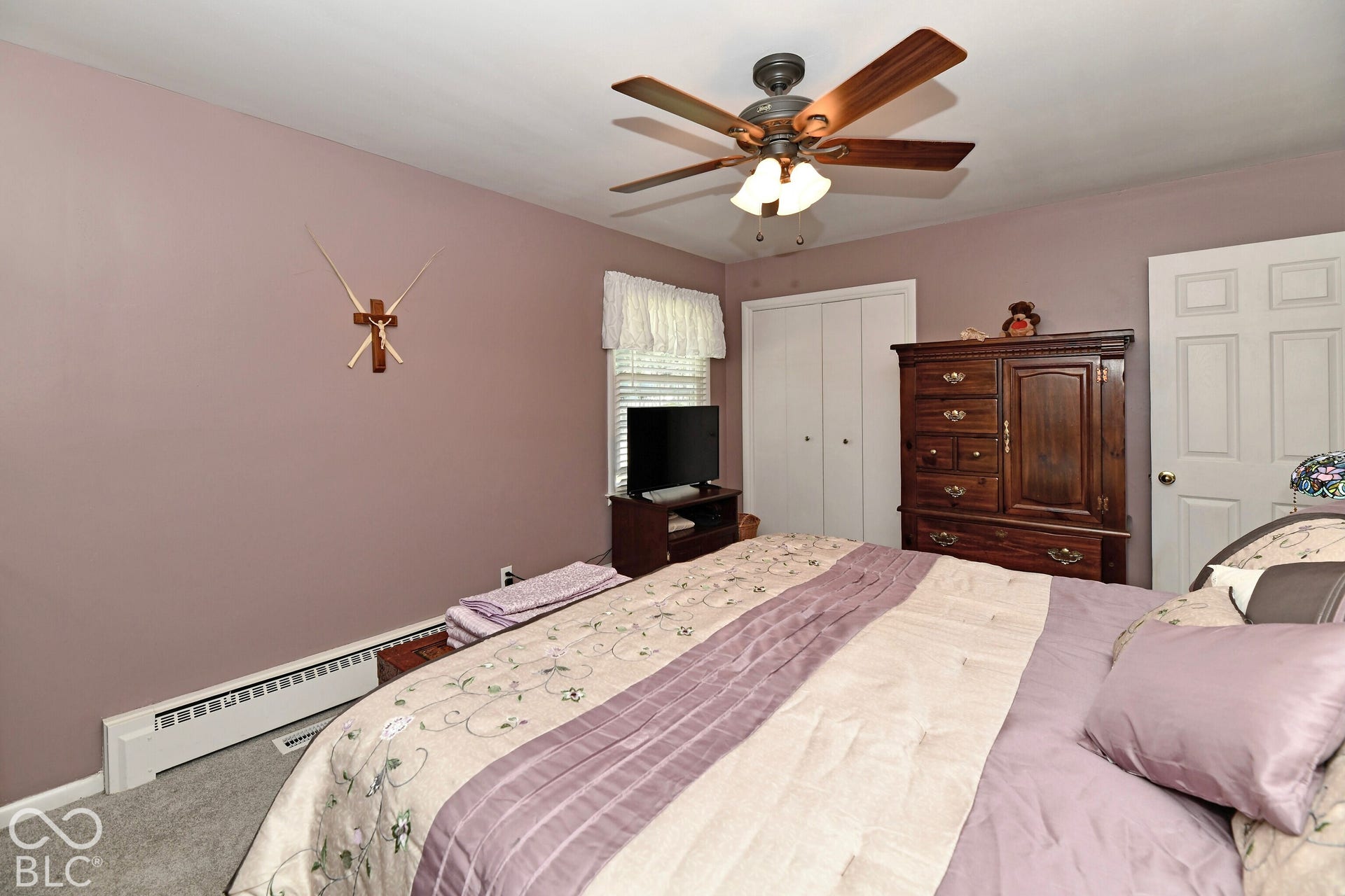 Room featuring neutral-toned carpeting, dual-panel closet doors, a multi-light ceiling fan, and a six-panel interior door