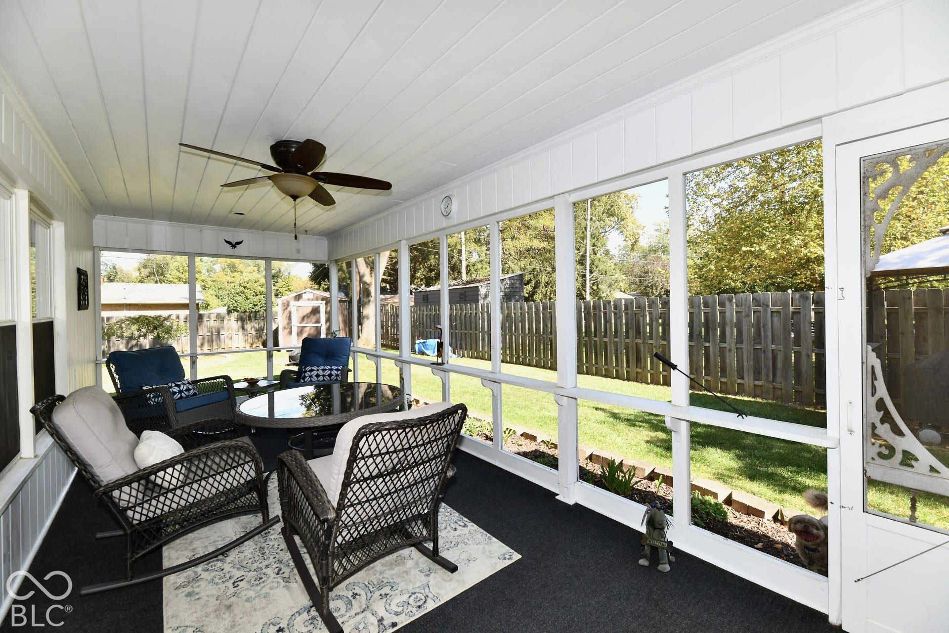 Screened porch featuring a paneled ceiling, ceiling fan, solid surface flooring, and full-height screen walls opening to a fenced backyard