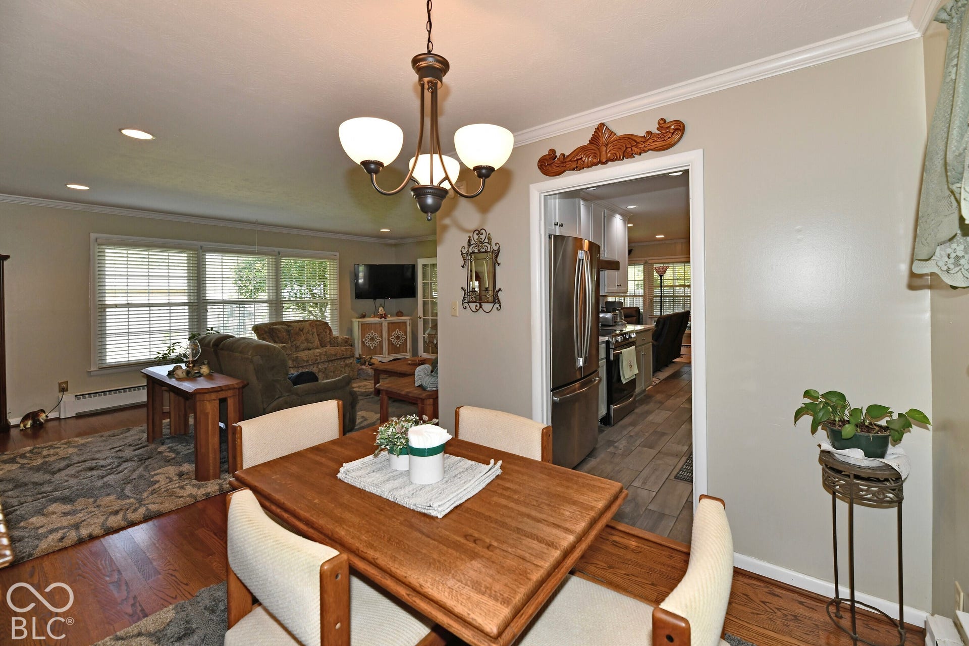 Dining area featuring hardwood flooring, crown molding, and an overhead chandelier with milk-glass shades