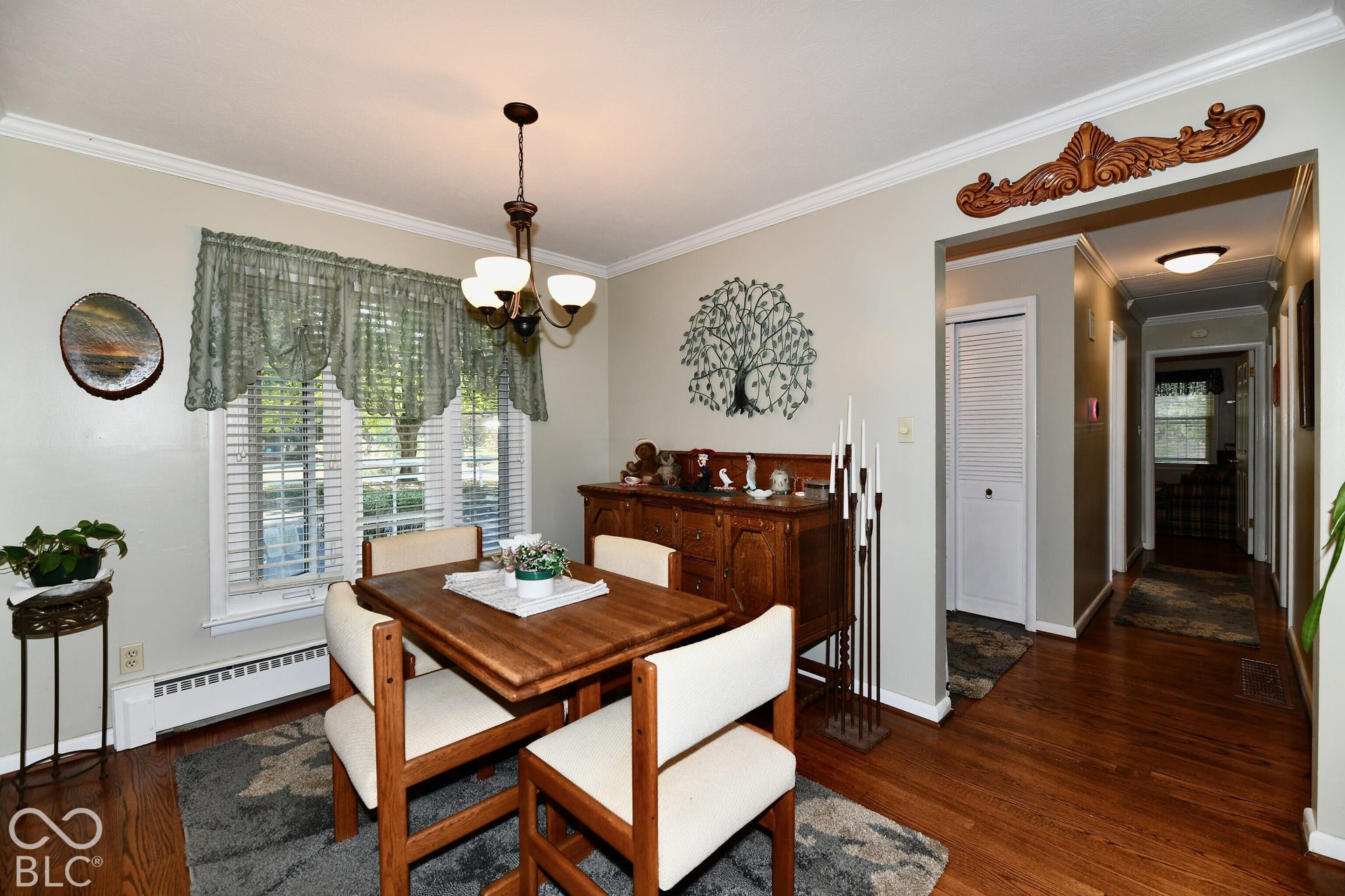 Dining area featuring wood-finish flooring, crown molding, a hanging light fixture, and decorative wood door header trim