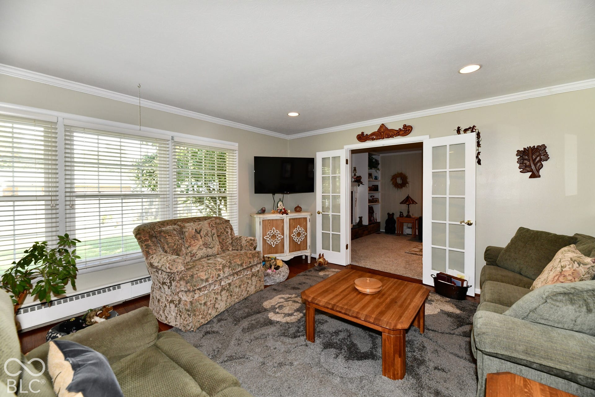 Large windows with horizontal blinds, recessed lighting, crown molding, and glass-paneled double doors