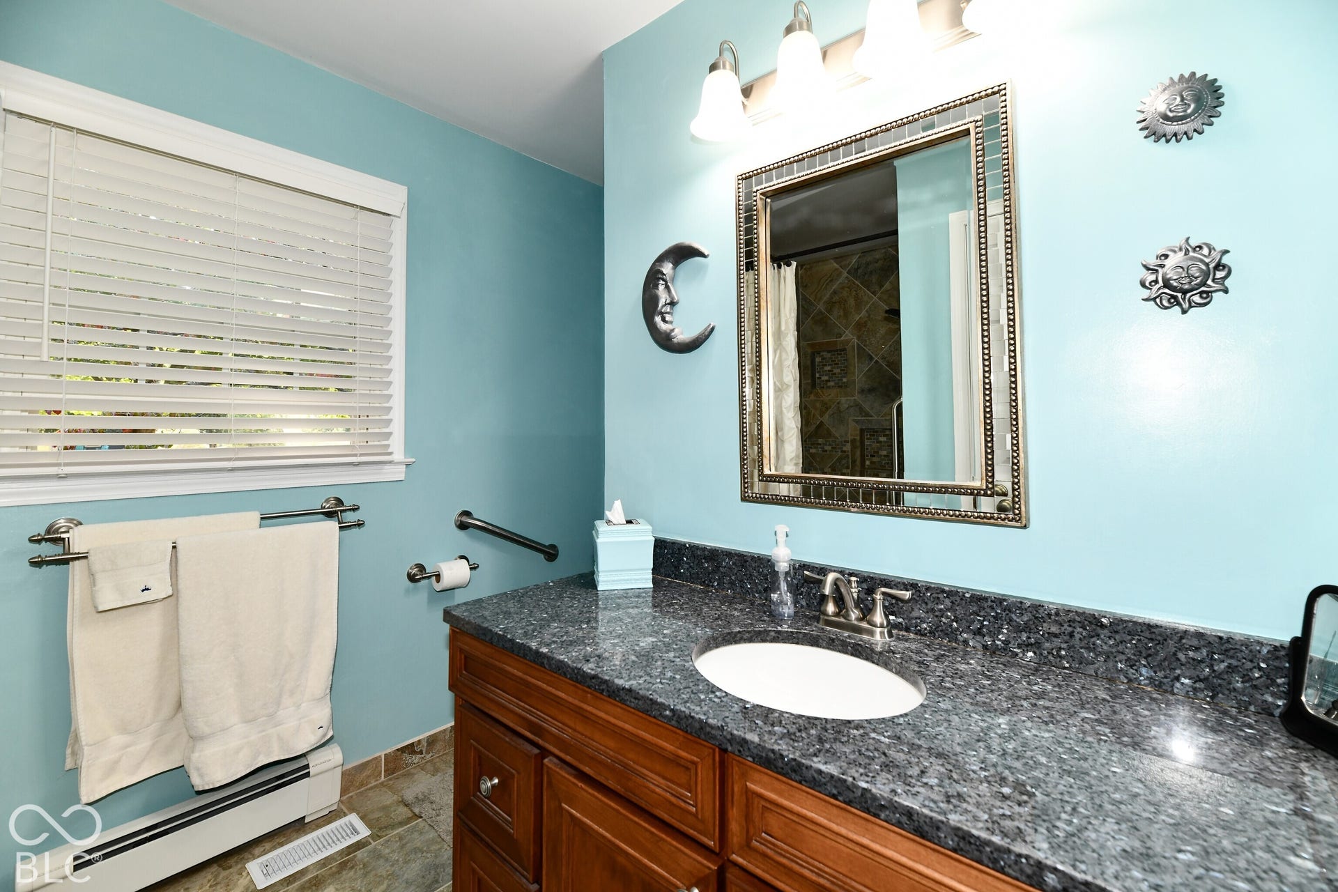Bathroom vanity featuring a stone countertop, an integrated undermount oval sink, wooden cabinetry, and a three-light wall-mounted fixture