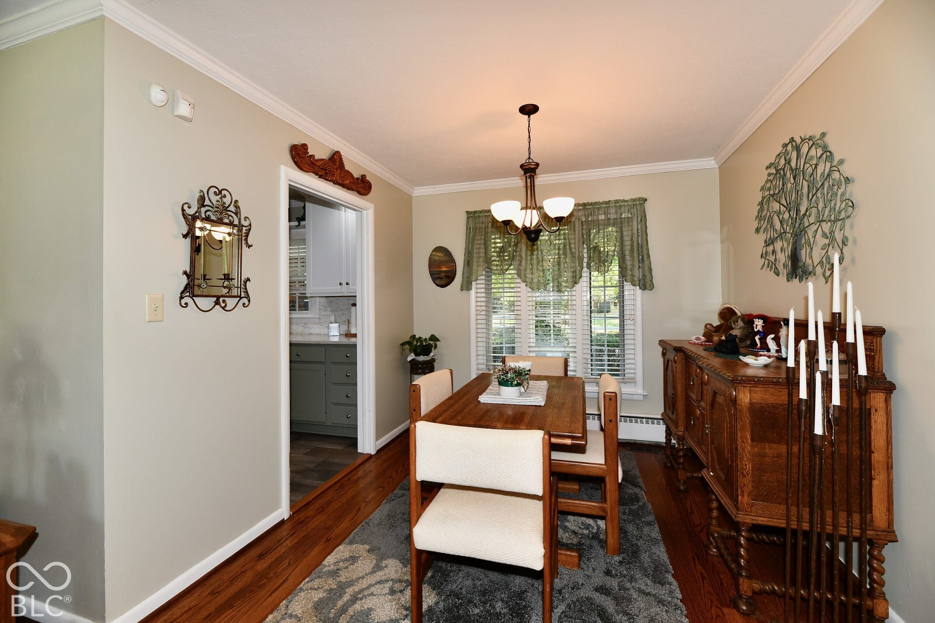 Dining area featuring hardwood flooring, crown molding, multi-light chandelier, and bay window