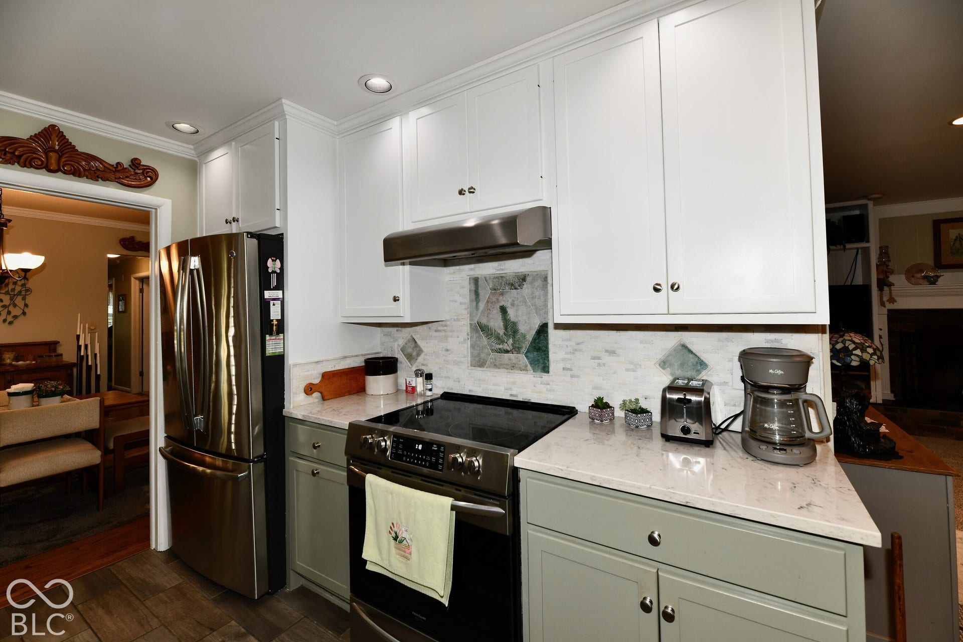 Kitchen featuring two-tone shaker-style cabinetry, stone-finish countertops, stainless steel appliances, recessed ceiling lighting, and a decorative tile backsplash with mosaic accents