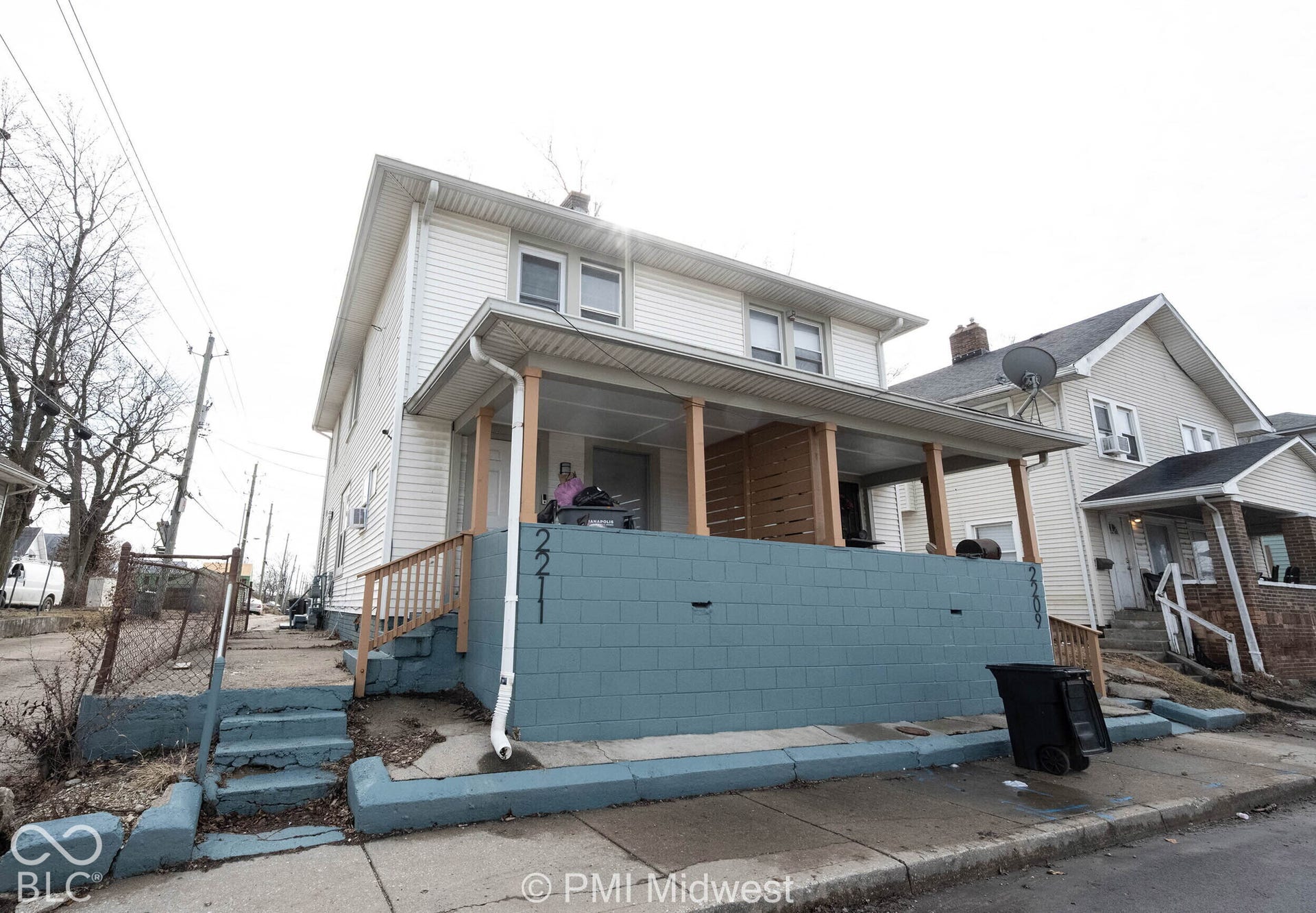 Two-story residence featuring light-colored horizontal siding, a covered front porch, and a raised masonry wall foundation
