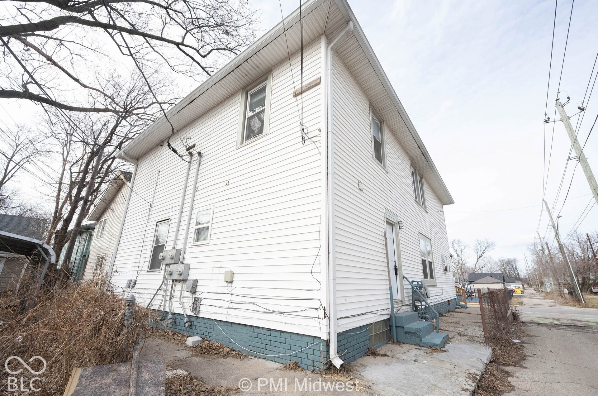 Two-story exterior featuring white horizontal siding and a painted masonry foundation