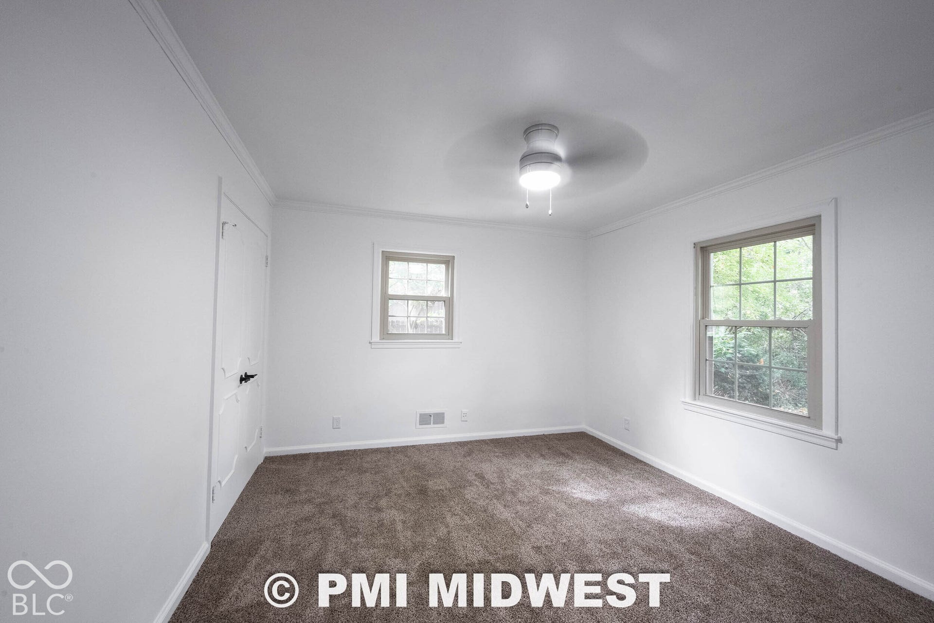 Neutral-toned carpeting, multi-pane windows, interior door with decorative molding, and ceiling-mounted light fixture