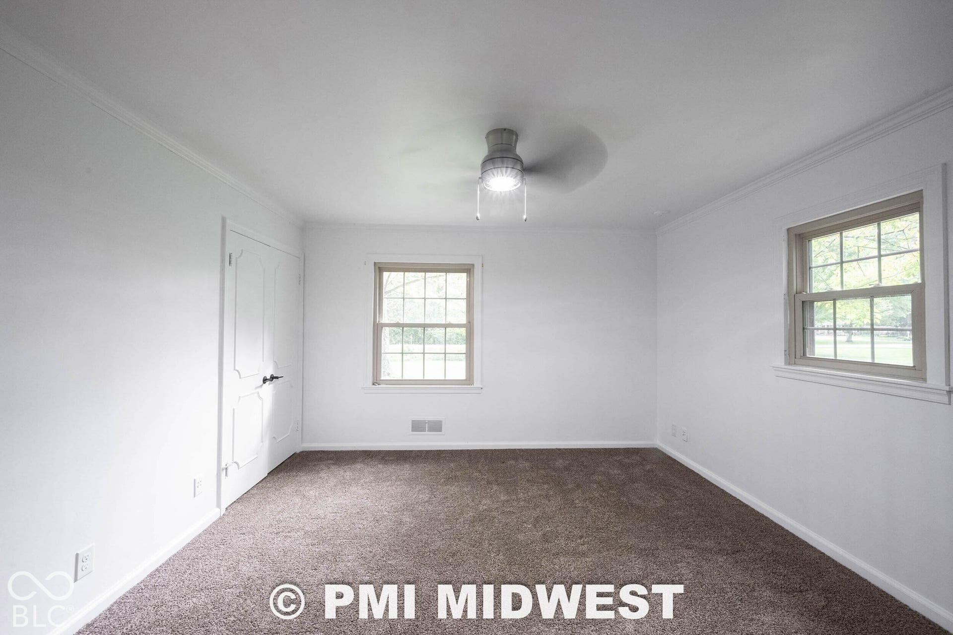 Interior room featuring neutral carpeting, a ceiling-mounted light fixture, crown molding, multi-pane windows with trim, and a paneled closet door