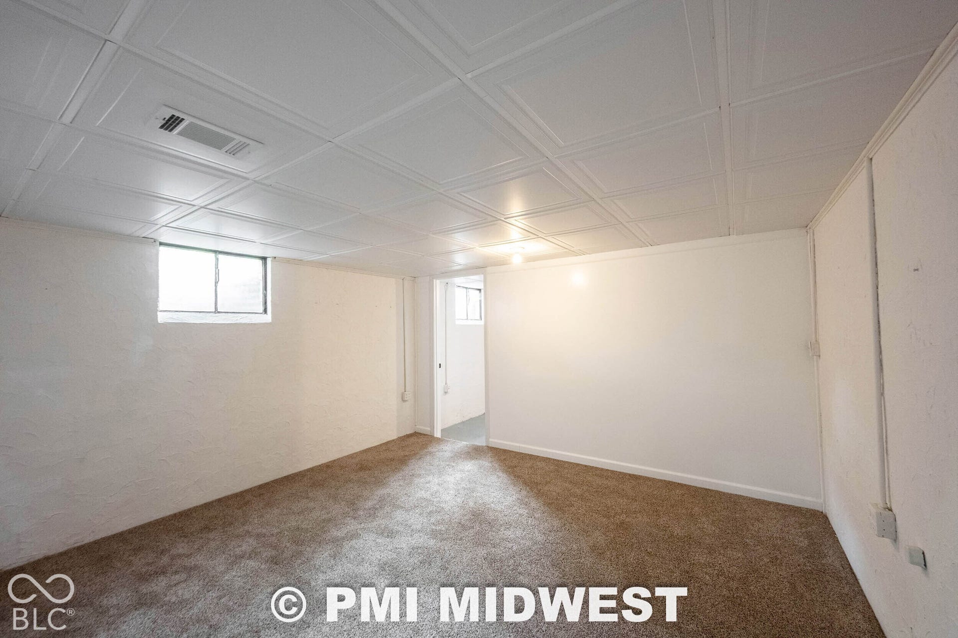 Interior space featuring textured walls, neutral carpeting, and a white paneled ceiling