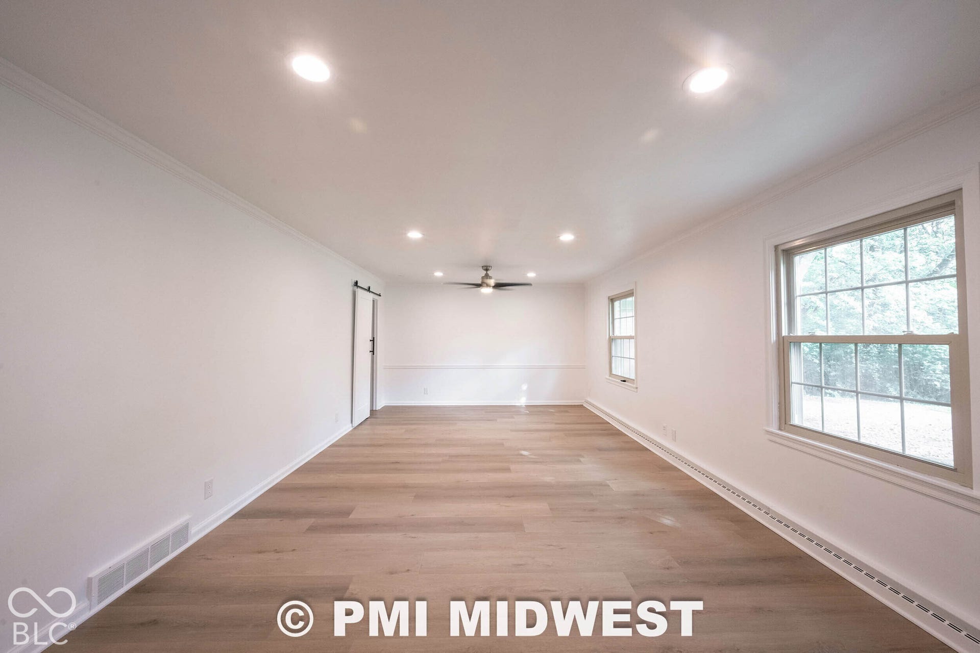 Room featuring wood-finish flooring, recessed lighting, double-hung windows, chair rail molding, and a sliding barn-style door