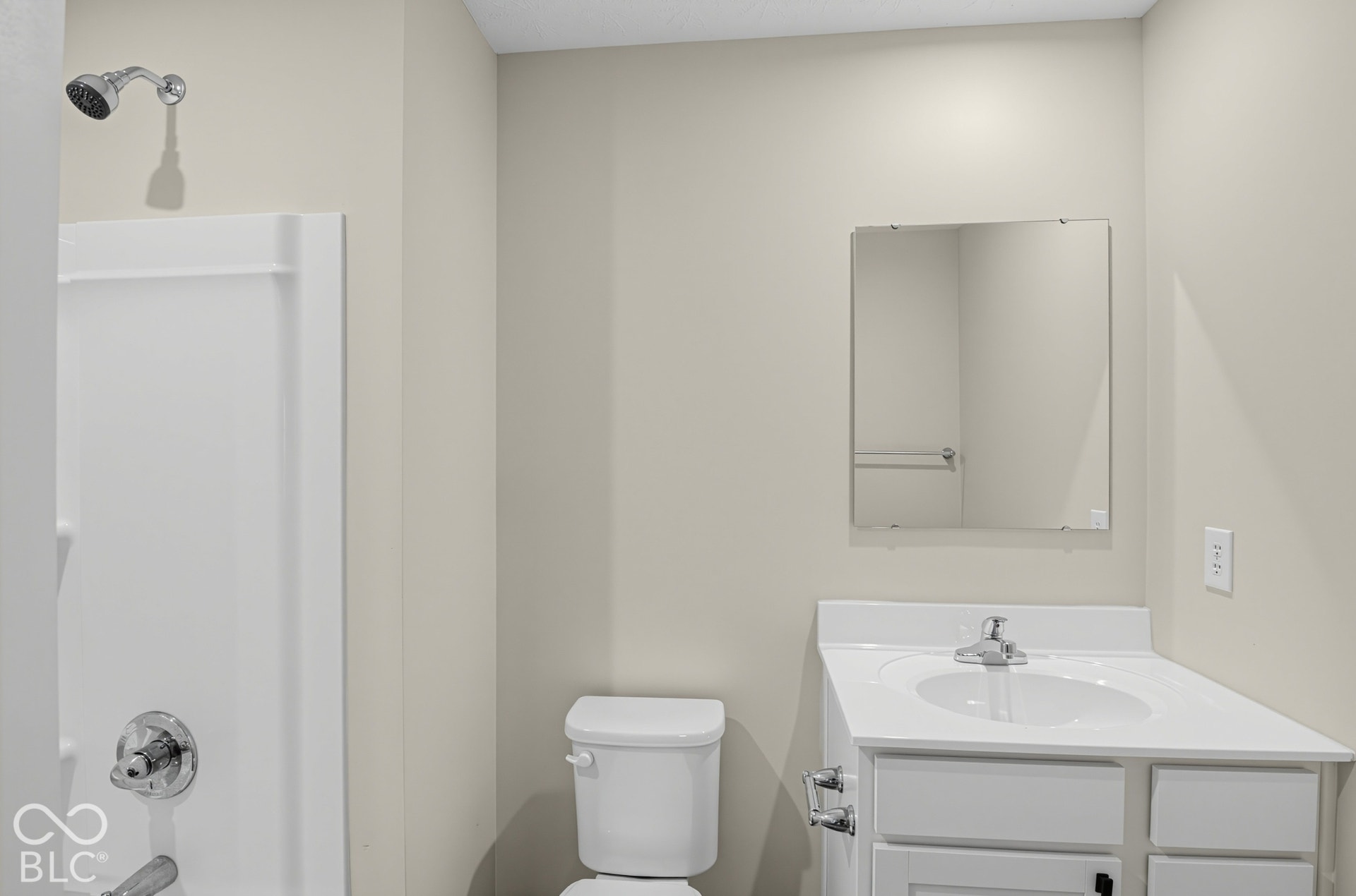 Bathroom featuring a white vanity with an integrated sink, a frameless wall-mounted mirror, and a tub-shower combination with chrome hardware