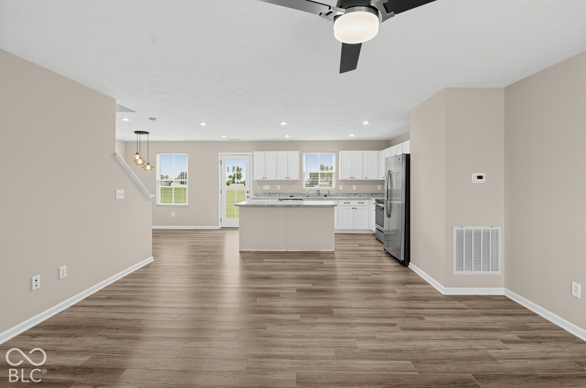 Open concept area featuring wood-finish flooring, white cabinetry, a kitchen island with stone-finish countertops, recessed lighting, and a modern ceiling fan