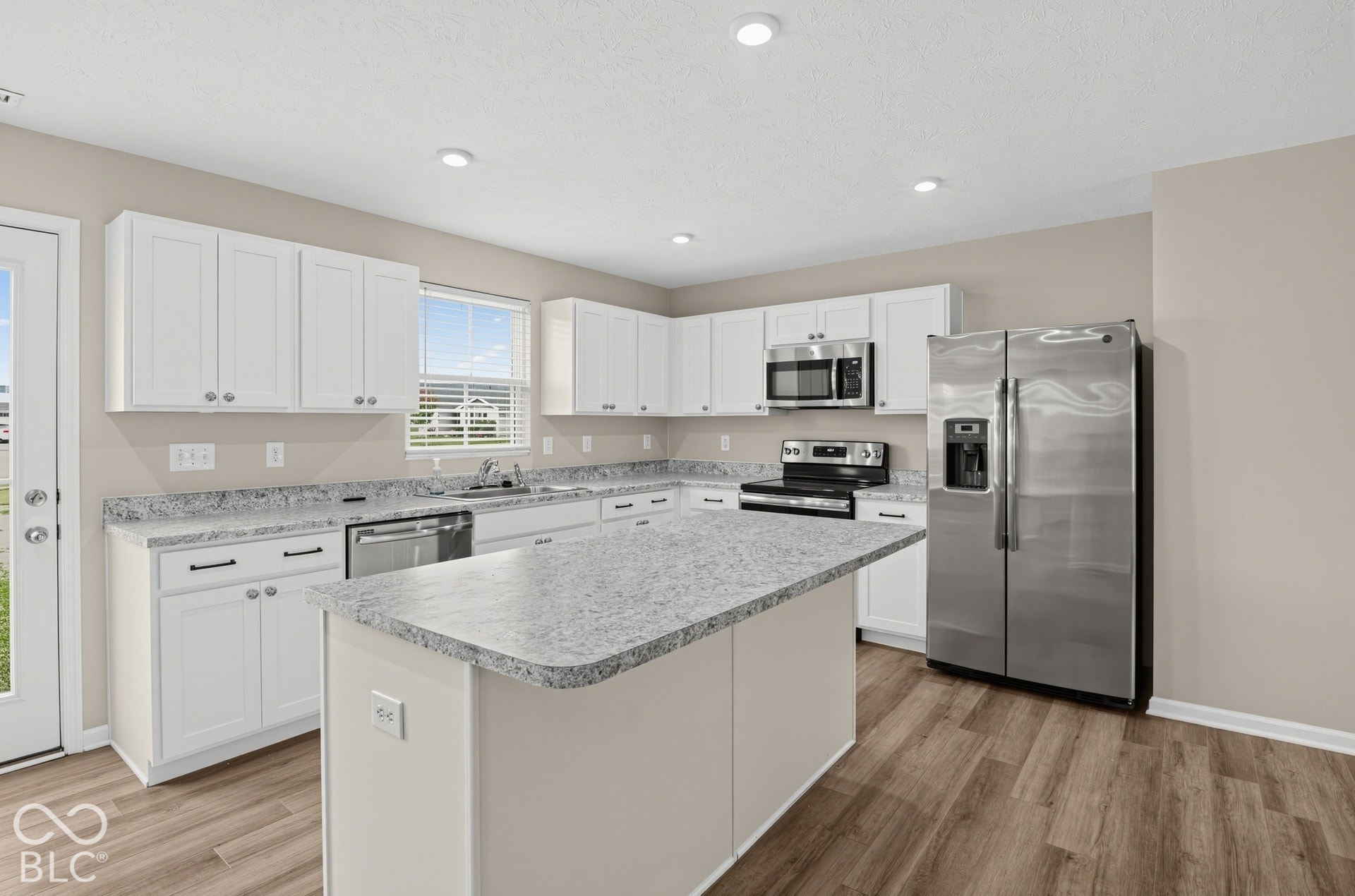 Kitchen featuring white cabinetry, stone-finish countertops, a central island, stainless steel appliances, and wood-finish flooring