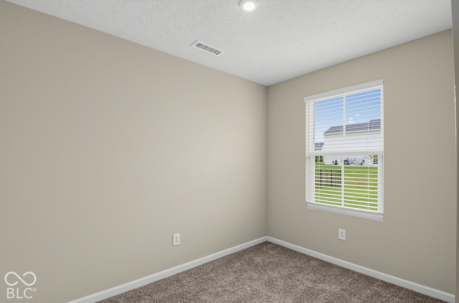 Neutral-toned interior space featuring neutral wall paint, wall-to-wall carpeting, and a single-pane window with installed horizontal blinds