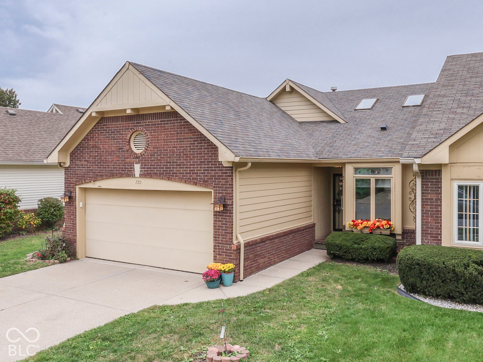 770 Ivy Lane, Greenwood, IN 46143 Exterior facade featuring a combination of brick and horizontal siding, an attached two-car garage, roof-integrated skylights, a recessed entry, and double-hung windows with grilles