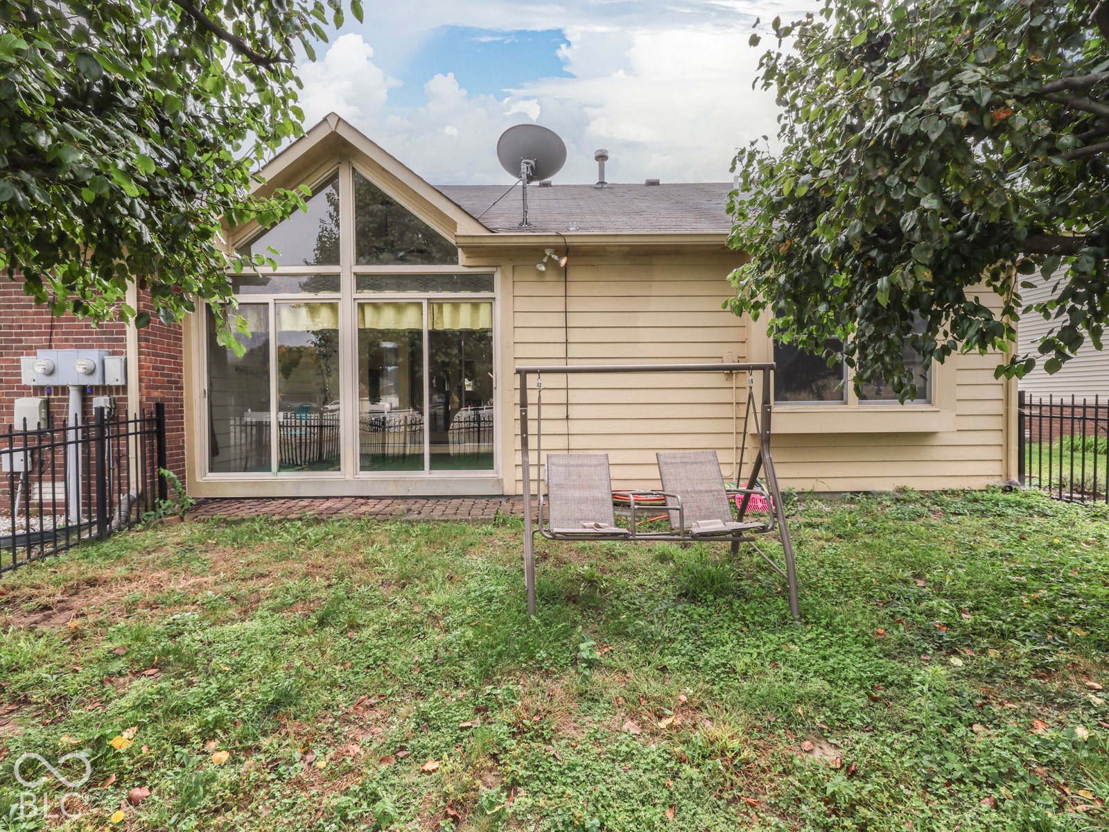 770 Ivy Lane, Greenwood, IN 46143 Exterior rear elevation featuring lap siding, an A-frame glass wall, brick masonry accents, a brick patio, and black metal fencing