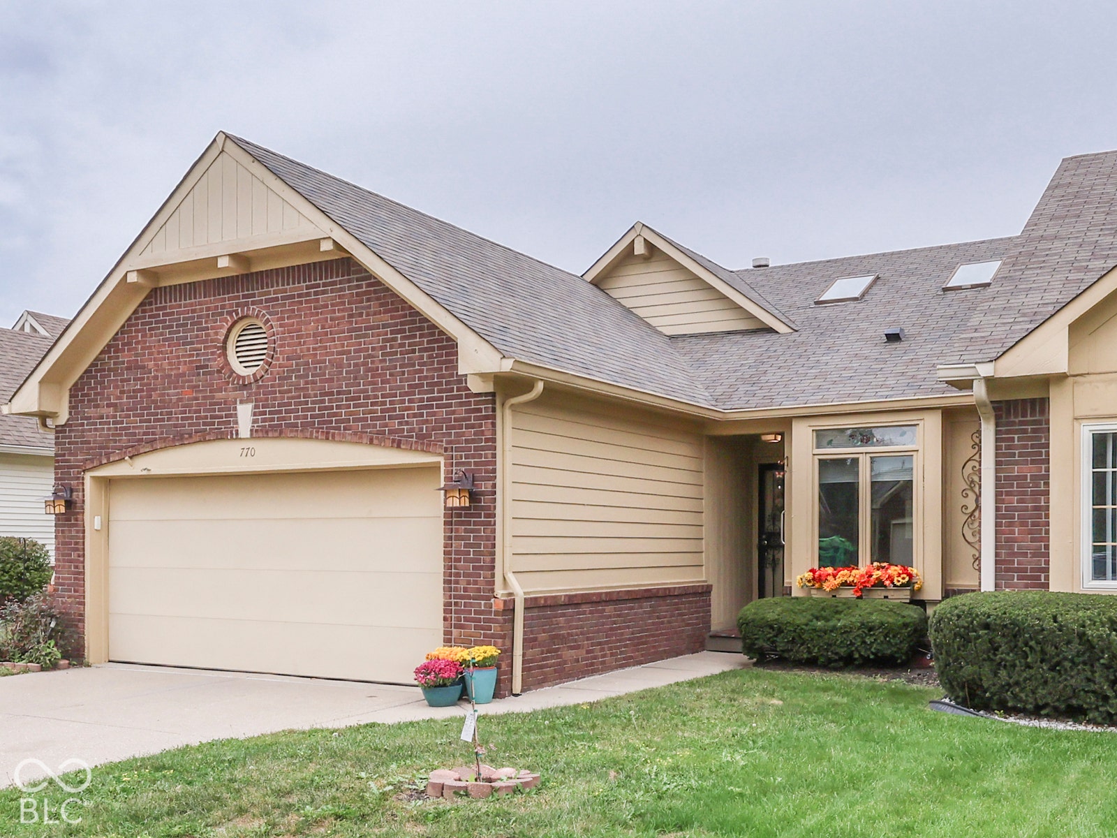 770 Ivy Lane, Greenwood, IN 46143 Brick and horizontal siding exterior featuring a gabled roofline, arched garage door entry, and roof-integrated skylights